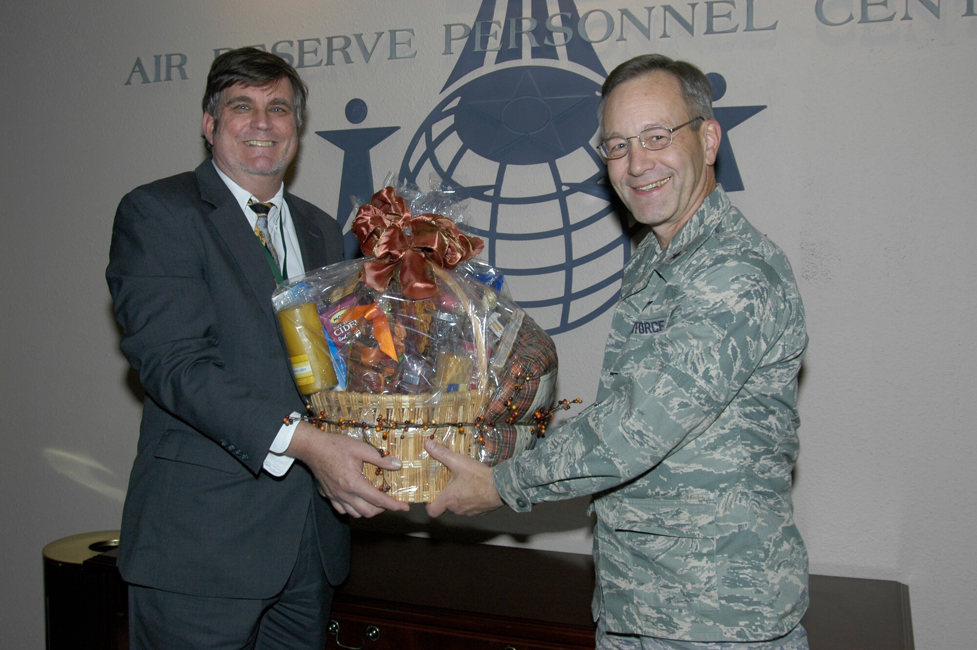 Brig. Gen. Eric Crabtree presents a Thanksgiving basket to Steve Hannan in the Schwing Conference Room on Nov. 20. Mr. Hannan won the basket by purchasing a bag of candy benefiting the Air Reserve Personnel Center holiday party. The fund-raiser earned $314. General Crabtree is the ARPC commander, and Mr. Hannan is the director of Communications and Information. (U.S. Air Force photo/Mike Molina)