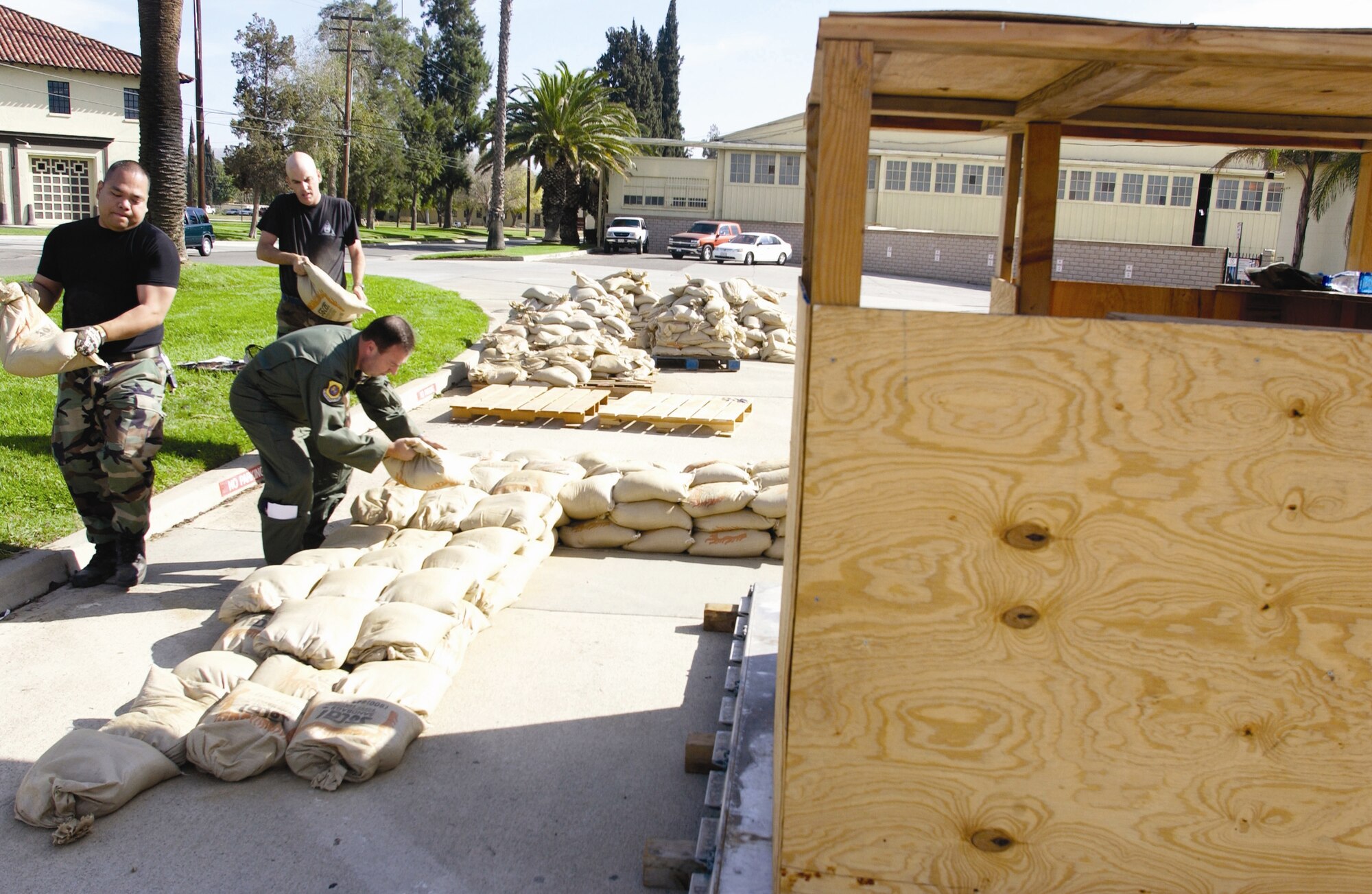 (L to R) Capt. Cyrus Macapagal, Col. Kevin Krebs and Master Sgt. Jim Biere stack over 500 sandbags in the parking lot of the 452nd Air Mobility Wing headquarters building. Midway into the process, other troops from around base joined in to help. They were participating in a hardening demo to increase awareness for the Operational Readiness Inspection in February that simulated building a four-foot high wall of sand bags around a designated structure. Select participants will be chosen to take part in five hardening demonstrations that will be graded by Air Mobility Command inspectors during the actual ORI. (U.S. Air Force photo by Amy Abbott)