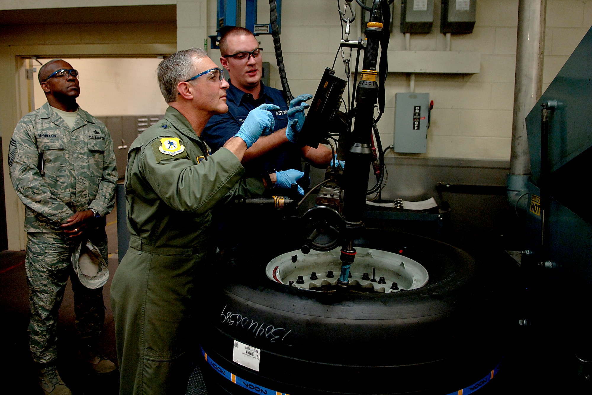 Maj. Gen. James Hawkins, 18th Air Force commander, and Airman 1st Class Stephen McFate, 437th Maintenance Squadron crew chief, tighten bolts on a tire Nov. 14 at the wheel and tire shop.(U.S. Air Force Photo/Senior Airman Nicholas Pilch)