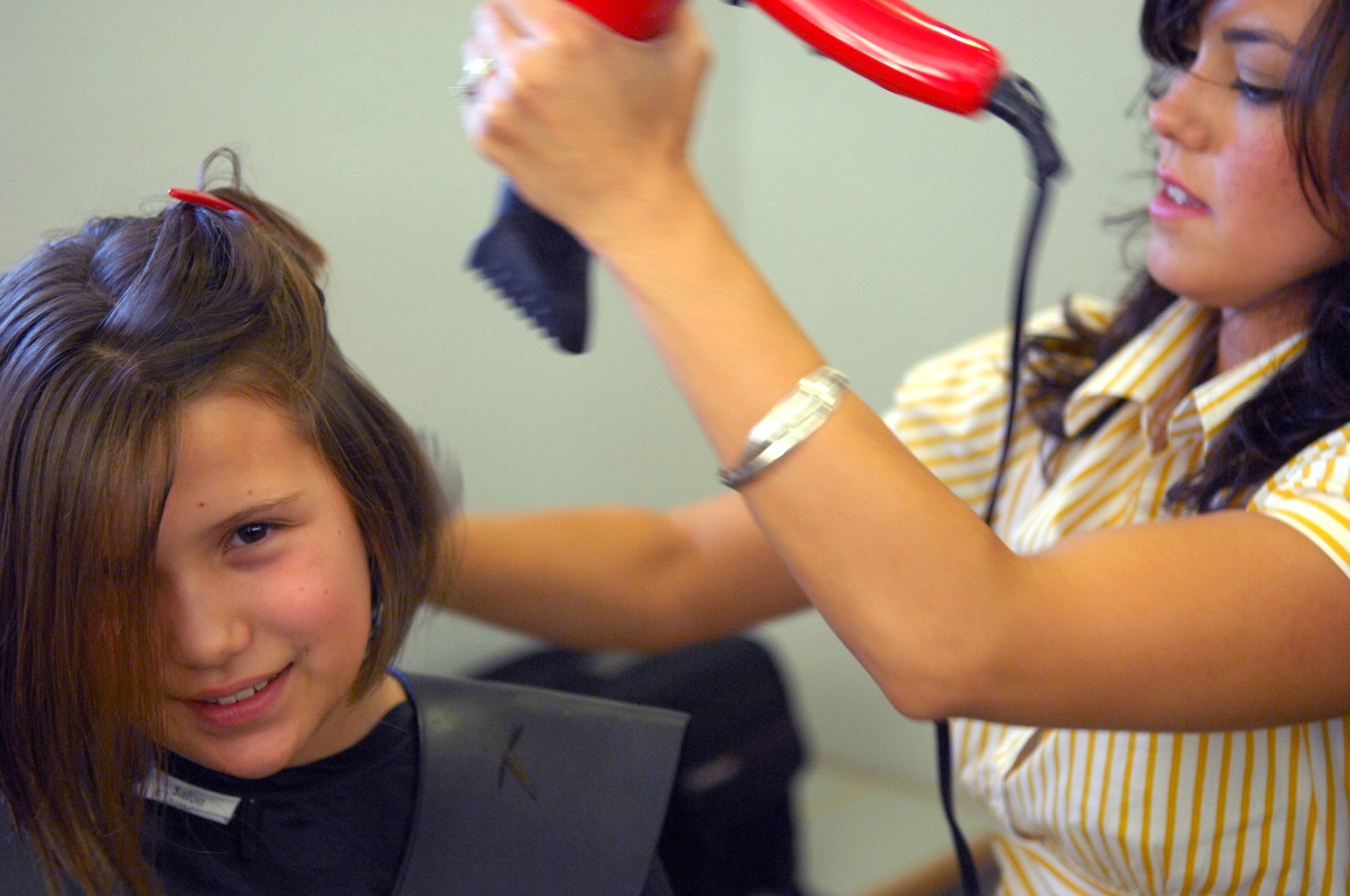 AVIANO AIR BASE, Italy-- Fourth grader Jordan Plaza gets her hair styled by volunteer Suzanne Couchman after donateing her hair  to Locks of Love. Aviano High School students Dylan Hillestad and Alex Simon organized the hair donation Nov.16, 2007.  Locks of Love is a public non-profit organization that provides hairpieces to financially disadvantaged children under age 18 suffering from long-term medical hair loss from any diagnosis. Locks of Love are unique by using donated hair to create the highest quality hair prosthetics. The prostheses provided by locks of love help to restore self-esteem and confidence, enabling children to face the world and their peers. For more information about Locks of love go to http://www.locksoflove.org   (U.S. Air Force photo/Staff Sgt. Michael R. Holzworth) 