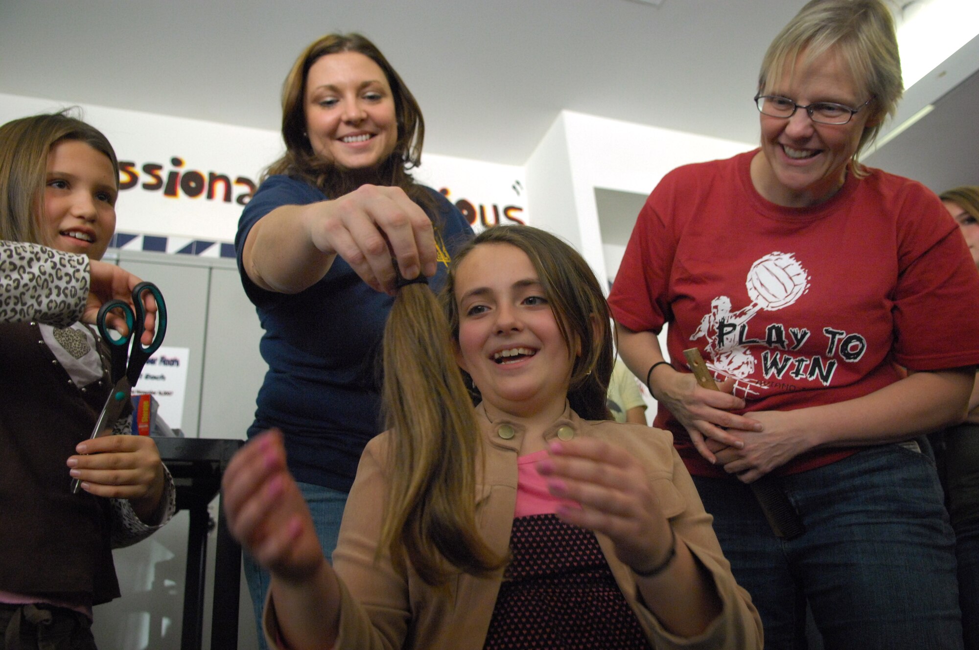 AVIANO AIR BASE, Italy-- Darlene Dittell a fourth grader at Aviano Elementary School laughs as Audrey Cooper and Pam Hillestad show her how much hair she just donated to Locks of Love. Aviano High School students Dylan Hillestad and Alex Simon organized the hair donation Nov.16, 2007.  Locks of Love is a public non-profit organization that provides hairpieces to financially disadvantaged children under age 18 suffering from long-term medical hair loss from any diagnosis. Locks of Love are unique by using donated hair to create the highest quality hair prosthetics. The prostheses provided by locks of love help to restore self-esteem and confidence, enabling children to face the world and their peers. For more information about Locks of love go to http://www.locksoflove.org   (U.S. Air Force photo/Staff Sgt. Michael R. Holzworth) 