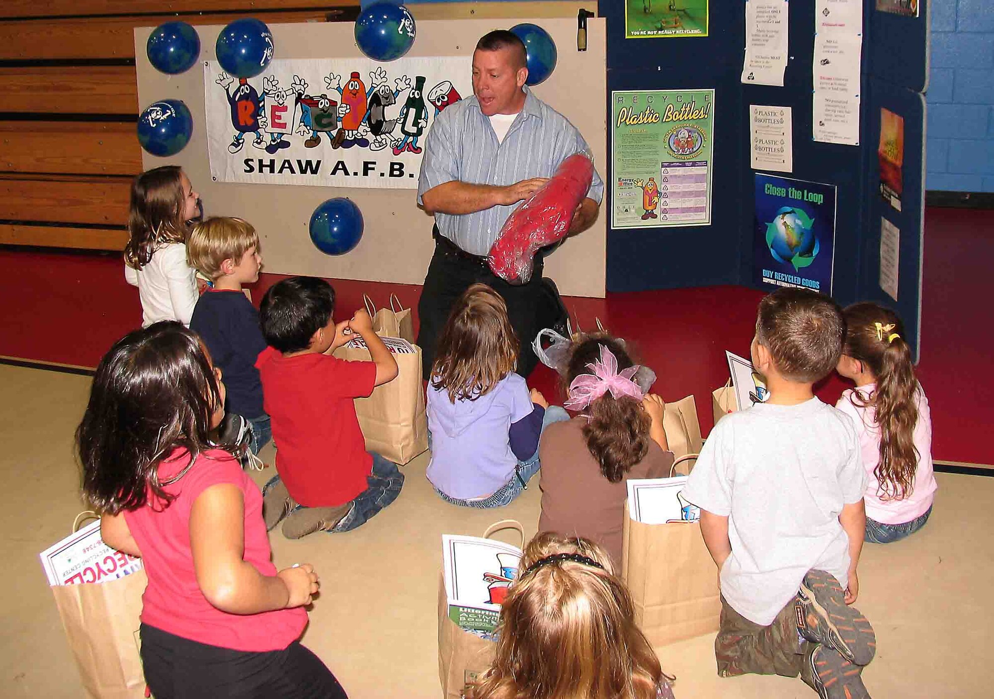 SHAW AIR FORCE BASE, S.C. -- Mr. Mark Hall, 20th Civil Engineer Squadron pollution prevention manager, sits in front of his "Magic Recycling Machine" Nov. 15 during America Recycles Day. Mr. Hall explains that the blanket he is showing the children is actually made from recycled plastic bottles. ARD is the only nationally recognized day dedicated to encouraging Americans to recycle and to buy recycled products. (Courtesy photo)
