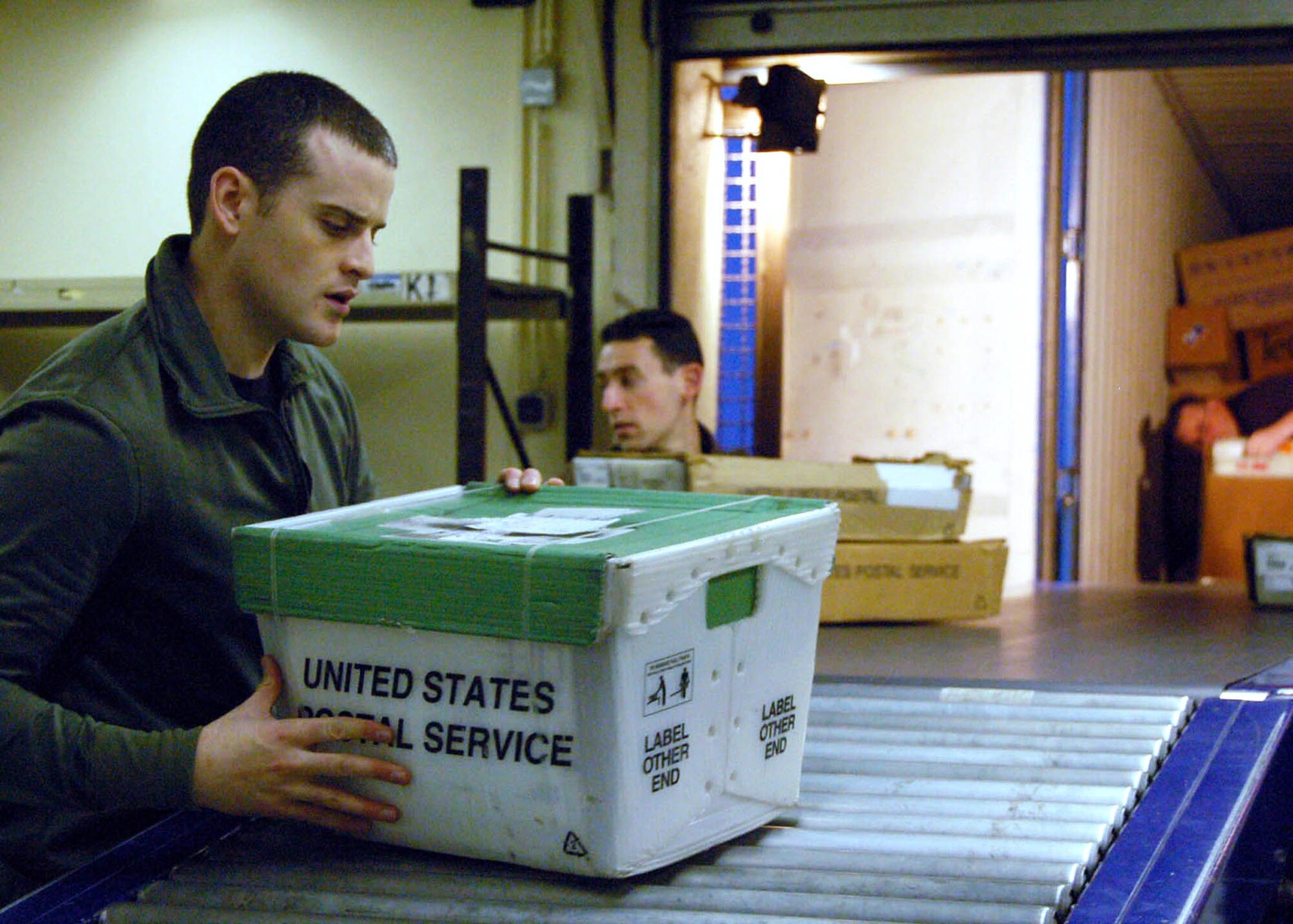SPANGDALHEM AIR BASE, Germany – (Left to right) Senior Airmen Ryan Chapman and Elliott Slade sort incoming mail as Staff Sgt. Royce Johnson unloads a mail truck. All Airmen are members of the 52nd Communications Squadron post office staff. During the holiday season, the approximately 35 person staff of postal Airmen, augmentees, civilians and volunteers process, stock, label and disseminate more than 1.2 million pounds of mail. (U.S. Air Force photo/Staff Sgt. Tammie Moore)