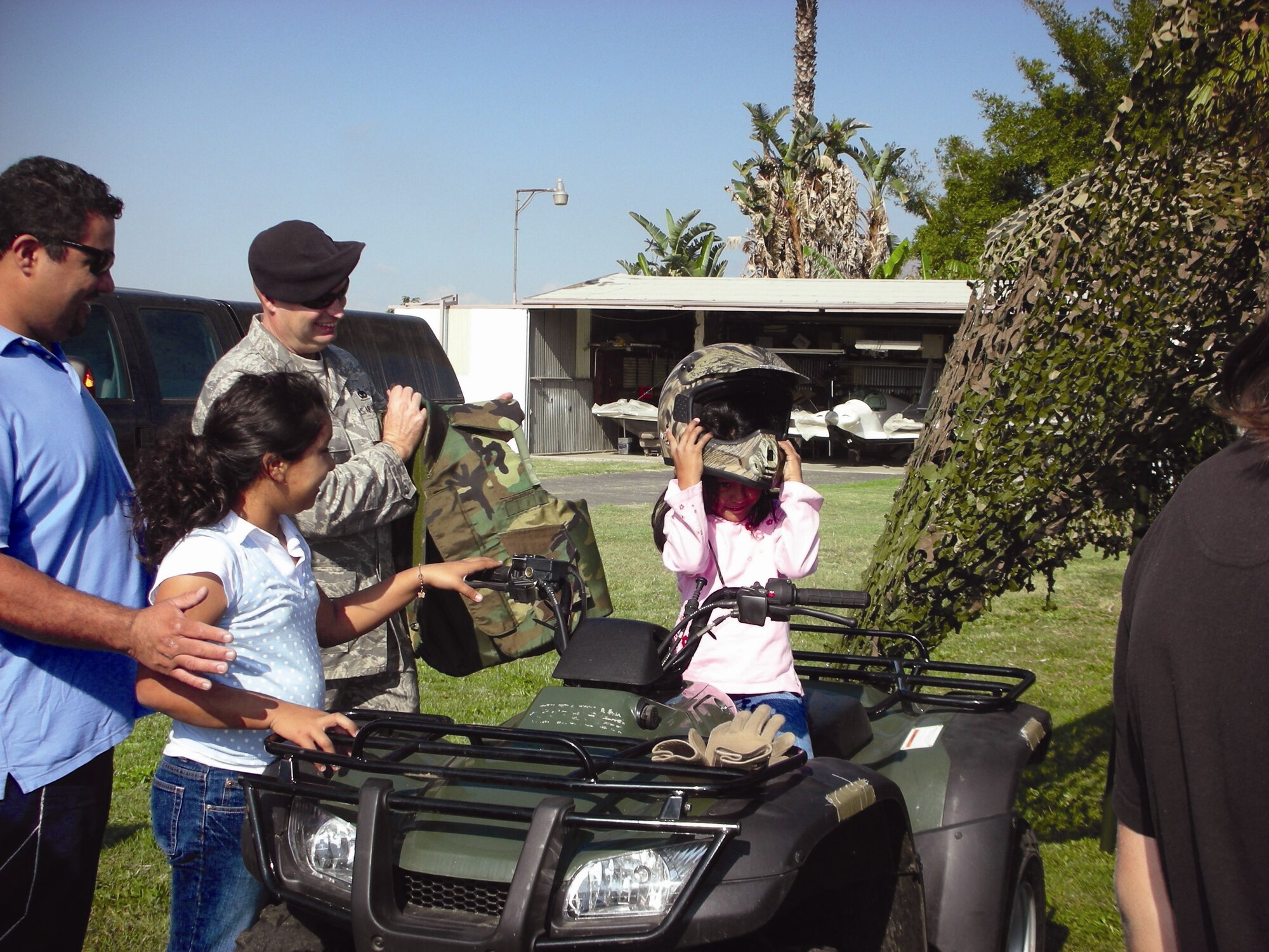 Technical Sgt. Sean Warman, March Air Reserve Base Security Forces, shows some of the children and their parents how to wear the flak equipment. (U.S. Air Force photos by 1st Lt. Mary Guest)