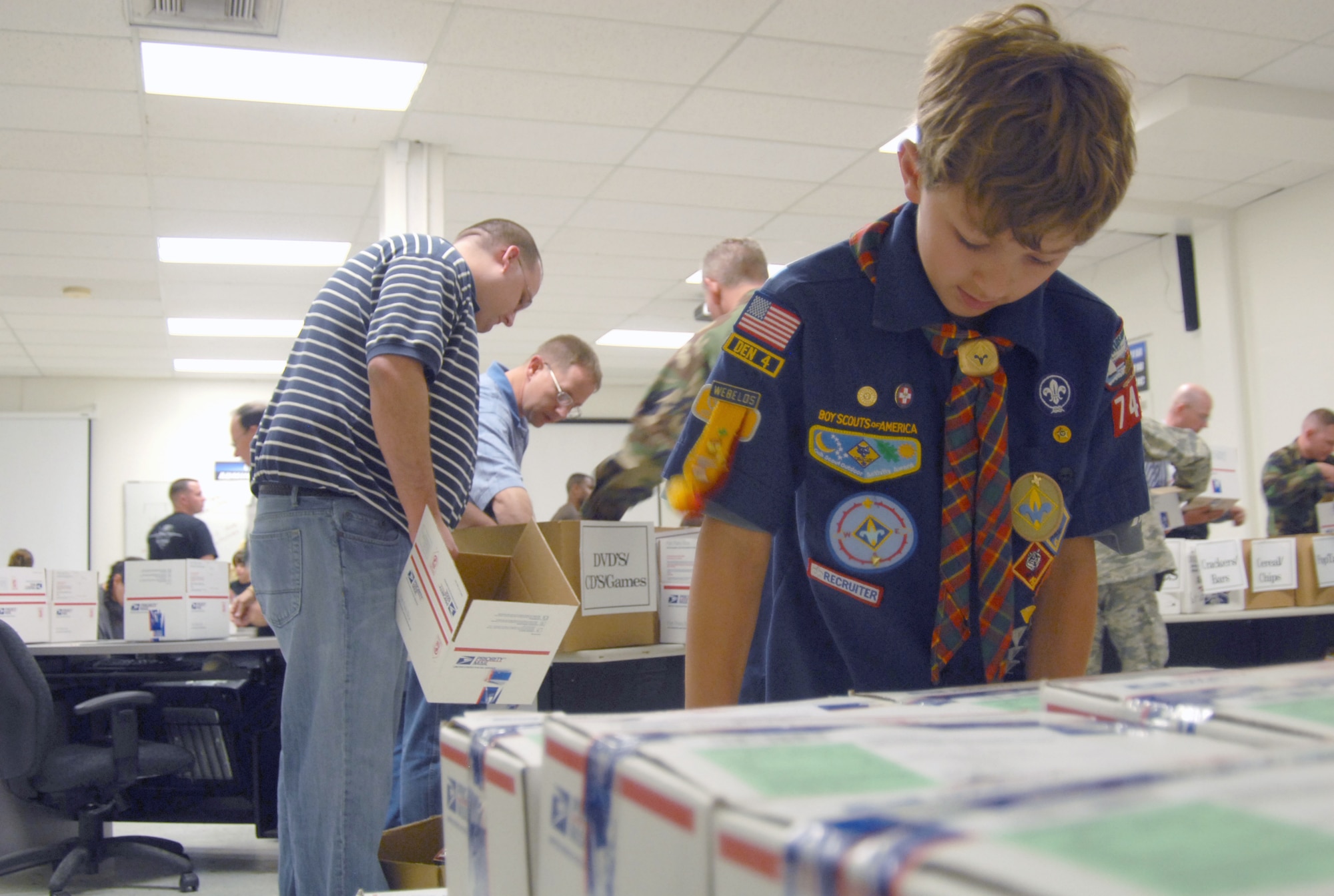 Josh Huck, a Cub Scout from Troop 741, stacks boxes during the Operation Touch Our Warriors II packing at building 2600 here Nov. 20. During the week of Nov. 12, volunteers set up booths in front of the Base Exchange and the Commissary and collected items needed by Edwards' deployed troops. (Photo by Senior Airman Julius Delos Reyes)
