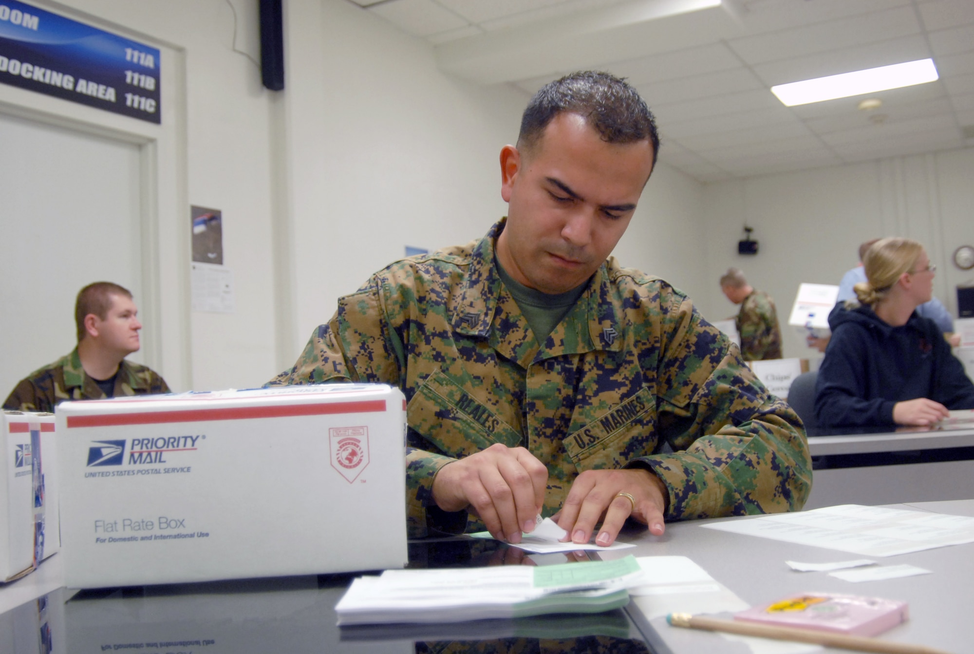 Marine Sgt. Juan Reales, Marine Heavy Helicopter Squadron 769 adjutant chief, places a label on a box during the Operation Touch Our Warriors II packing at building 2600 here Nov. 20. Volunteers packed 82 care packages for Edwards' deployed troops. (Photo by Senior Airman Julius Delos Reyes)