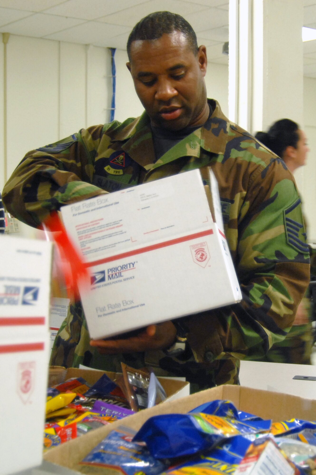 Master Sgt. Clay Slaton, 31st Test and Evaluation Squadron bomber weapons supervisor, places snacks on a box during the Operation Touch Our Warriors II packing Nov. 20 at building 2600 here. Operation Touch Our Warriors is a program that ensures Edwards' deployed troops receive gifts for the holidays. (Photo by Senior Airman Julius Delos Reyes)