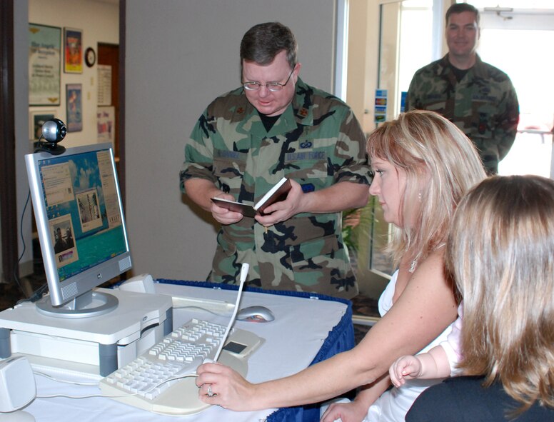 Maj. Mark McDaniel, 301st Fighter Wing Chaplain, recites wedding vows for Dr. Heather Cox and Marine Staff Sgt. Erik Mortenson (on Web cam) during a ceremony that took place recently at the Desert Storm Conference Center at Naval Air Station Joint Reserve Base Fort Worth, Texas. Dr. Cox, now Mrs. Erik Mortenson, connected over the Internet via Web cam to Sergeant Mortenson in Iraq to marry after both sides overcame many obstacles. (U.S. Air Force Photo/Tech. Sgt. Julie Briden-Garcia)