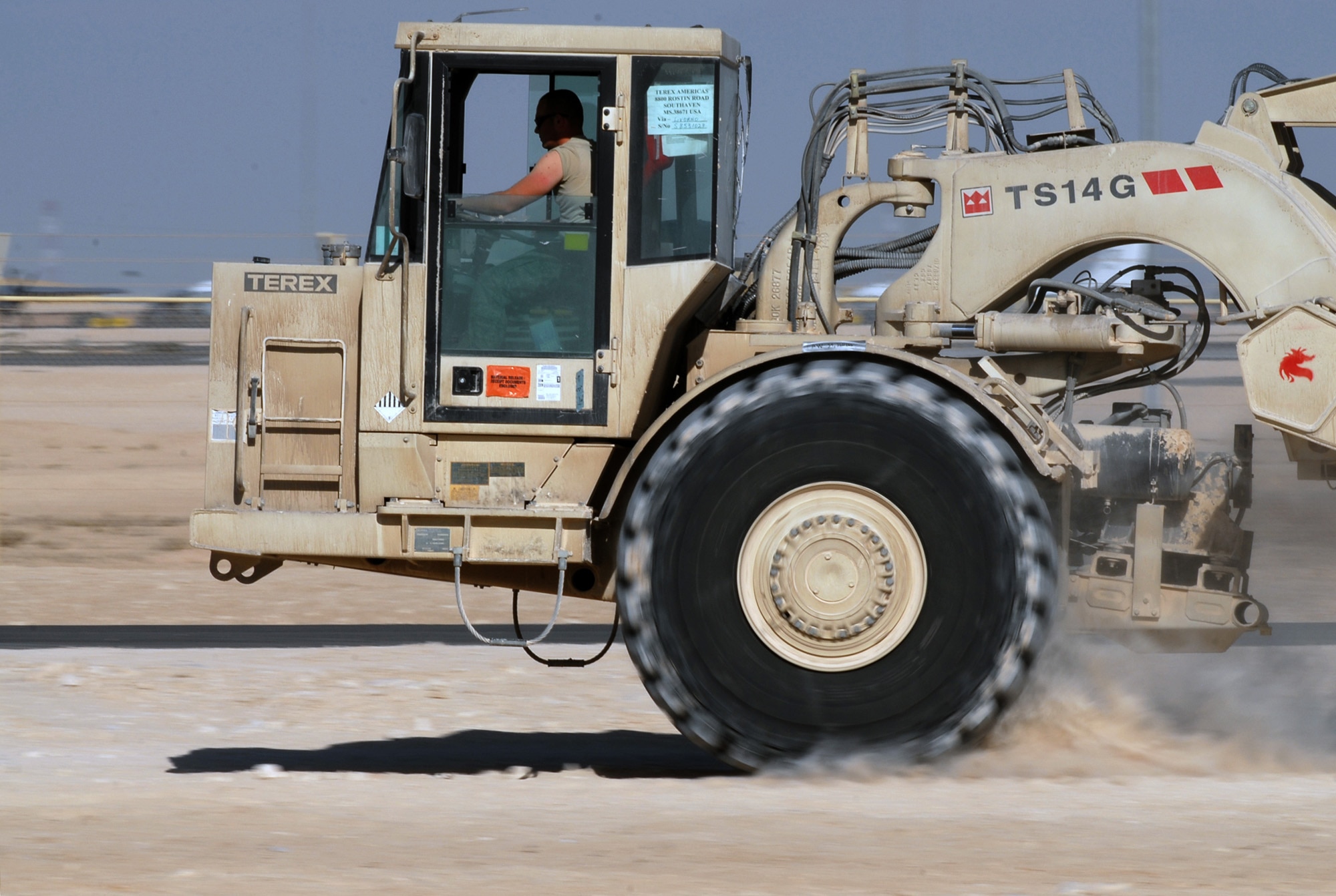 SOUTHWEST ASIA - Airman 1st Class Brandon Lynch, First Expeditionary RED HORSE Group, operates a scraper to shift dirt from a high spot of a pad site to fill in a low spot at a Southwest Asia air base. ( U. S. Air Force photo/Staff Sgt. Douglas Olsen)