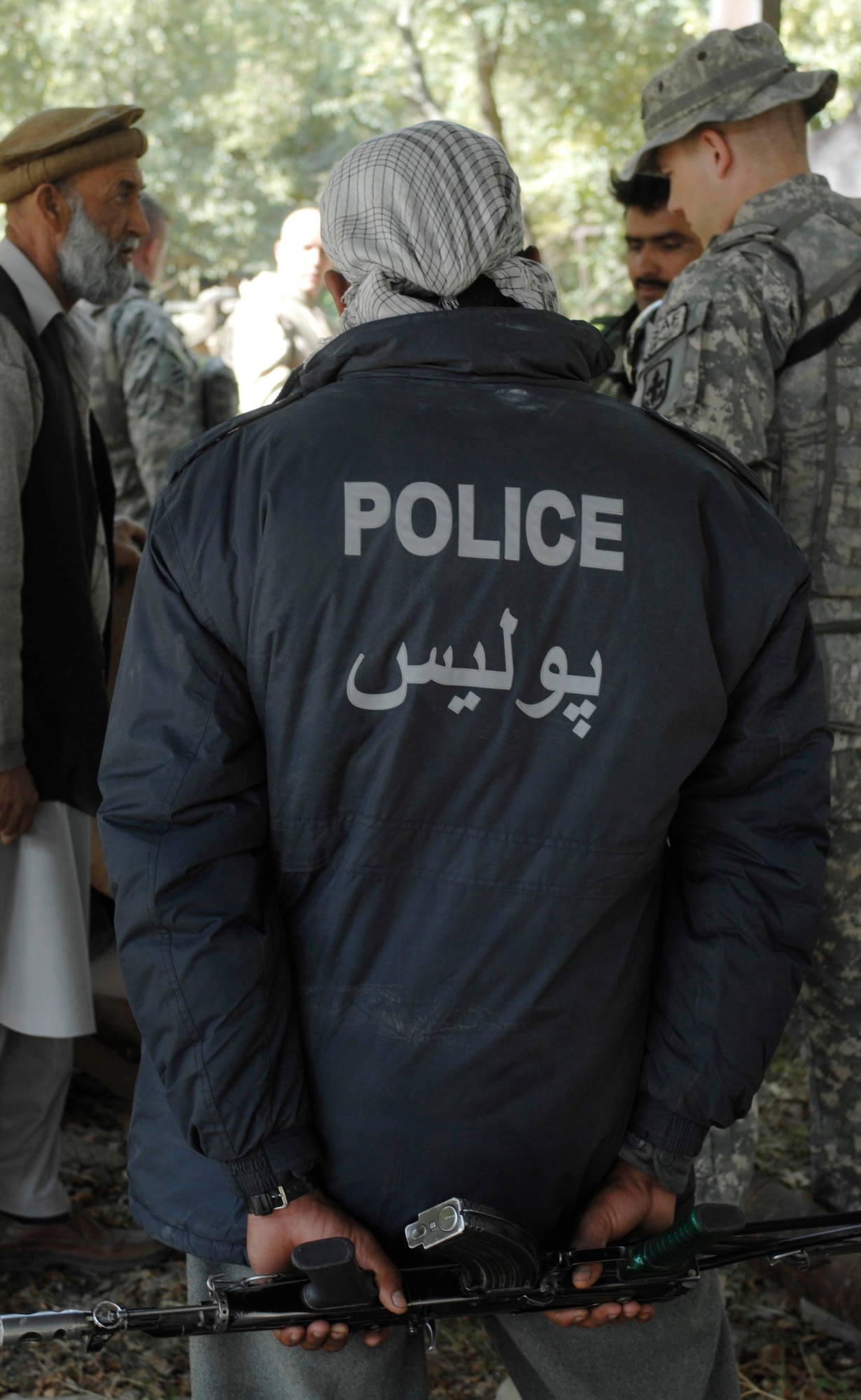 NANGARHAR PROVINCE, Afghanistan - An Afghan National police officer listens to the conversation between Afghan metal workers and Nangarhar Provincial Reconstruction Team members during an evaluation of a local metal working shop, Nov. 6, 2007.  The Nangarhar PRT is a joint team of Airman, Soldiers, and representatives from the U.S. Department of State, U.S. Agency for International Development, and the U.S. Department of Agriculture.  The team is responsible for helping the Government of the Islamic Republic of Afghanistan improve security, governance and promote reconstruction in Nangarhar Province.  The PRT assesses community needs and then builds schools, government centers, roads, medical capability and basic infrastructure throughout Nangarhar; they also personally mentor Afghan government officials and security forces to provide the Afghan people with the state representation and security they need.
(U.S. Air Force photo / Staff Sgt. Joshua T Jasper)  (Released)

