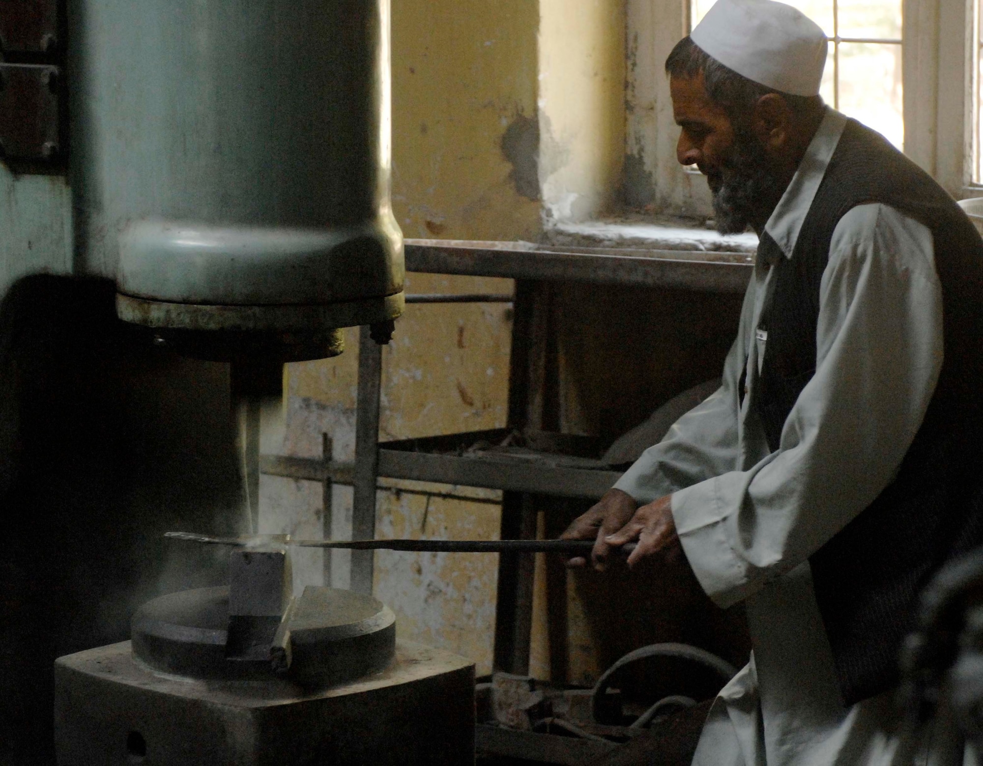 NANGARHAR PROVINCE, Afghanistan - An Afghan engineer demonstrates the operation of a metal shaper during a visit by the Nangarhar Provincial Reconstruction Team to a local metal working shop, Nov. 6, 2007.  The Nangarhar PRT is a joint team of Airman, Soldiers, and representatives from the U.S. Department of State, U.S. Agency for International Development, and the U.S. Department of Agriculture.  The team is responsible for helping the Government of the Islamic Republic of Afghanistan improve security, governance and promote reconstruction in Nangarhar Province.  The PRT assesses community needs and then builds schools, government centers, roads, medical capability and basic infrastructure throughout Nangarhar; they also personally mentor Afghan government officials and security forces to provide the Afghan people with the state representation and security they need.
(U.S. Air Force photo / Staff Sgt. Joshua T Jasper)  (Released)
