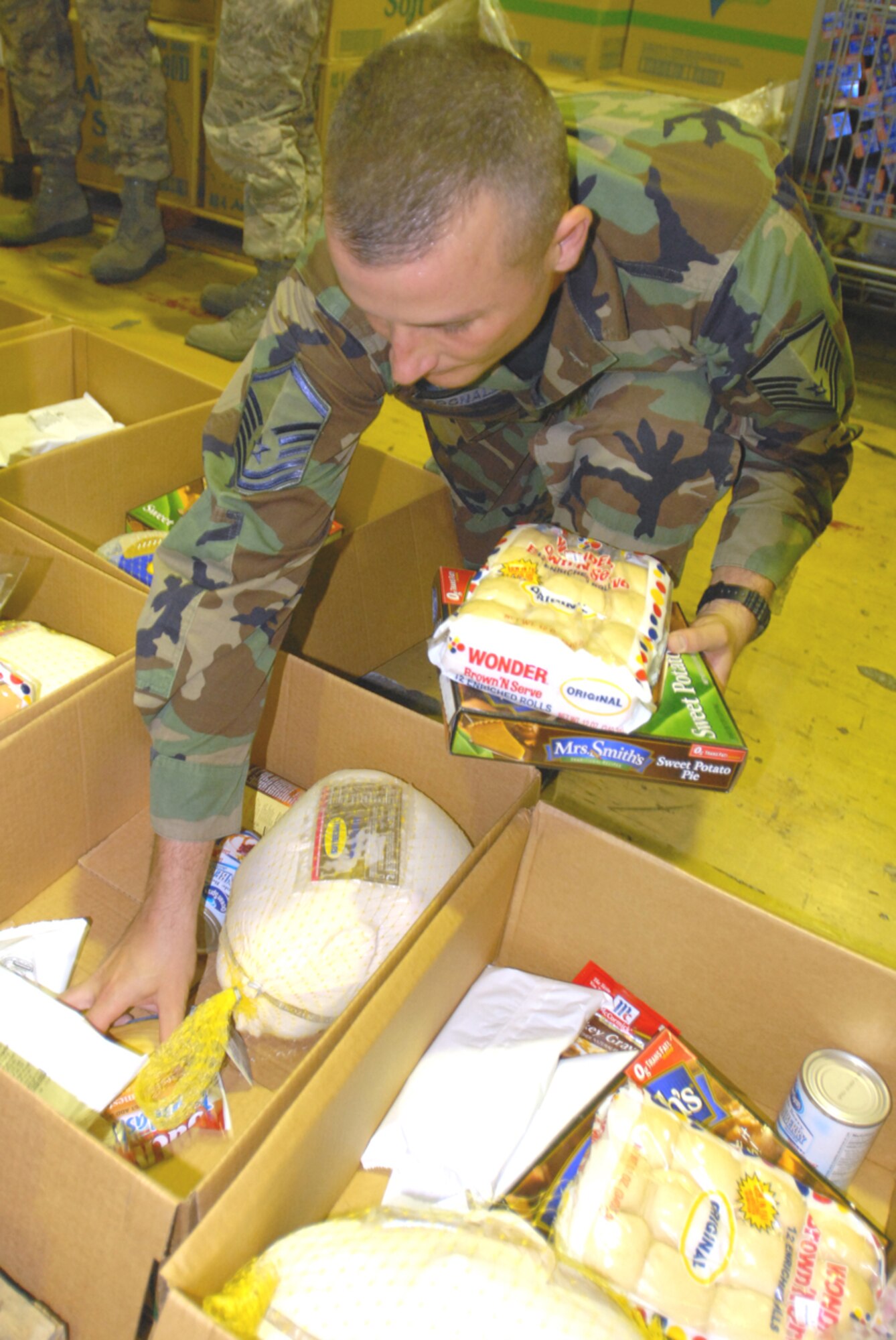 Master Sgt. Brian McDonald, 18th Operations Support Squadron, places food into  Thanksgiving food baskets for Operation Warm Heart. (U.S. Air Force/Airman 1st Class Kasey Zickmund)
