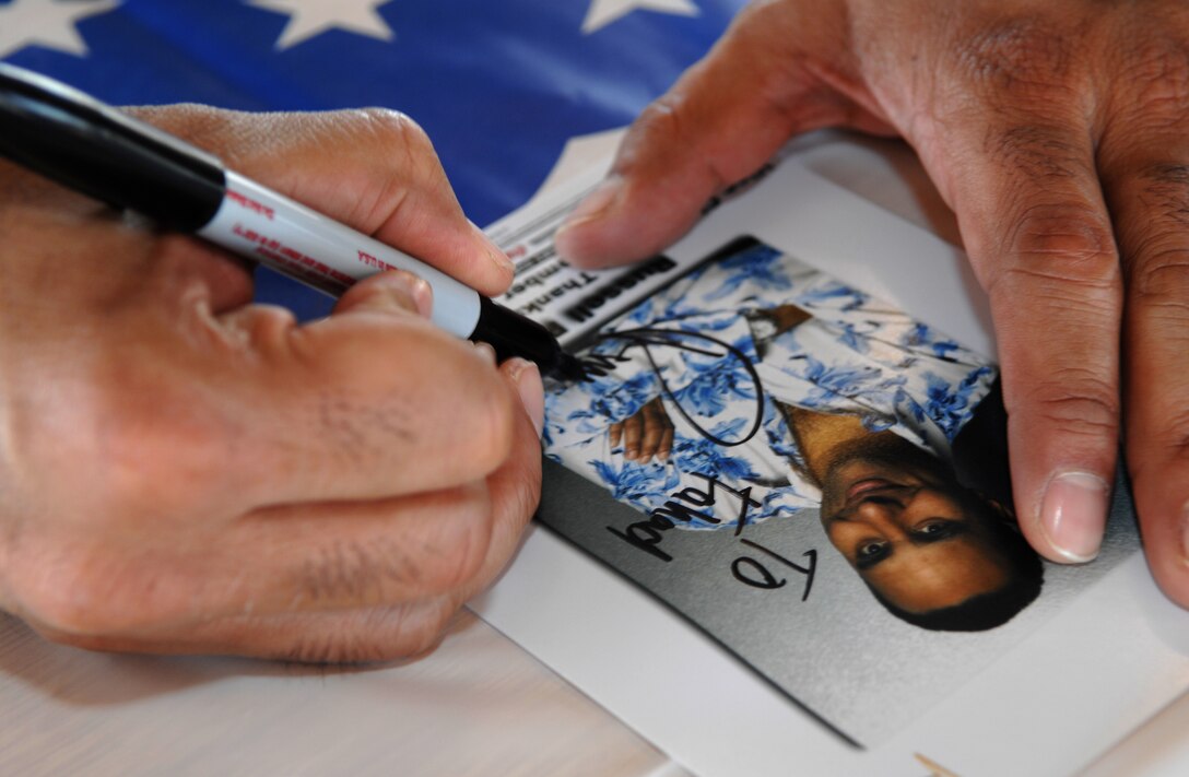 Comedian Russell Peters signs a picture for a soldier following a USO show on Kandahar Air Base, Afghanistan, Nov. 21, 2007. 
