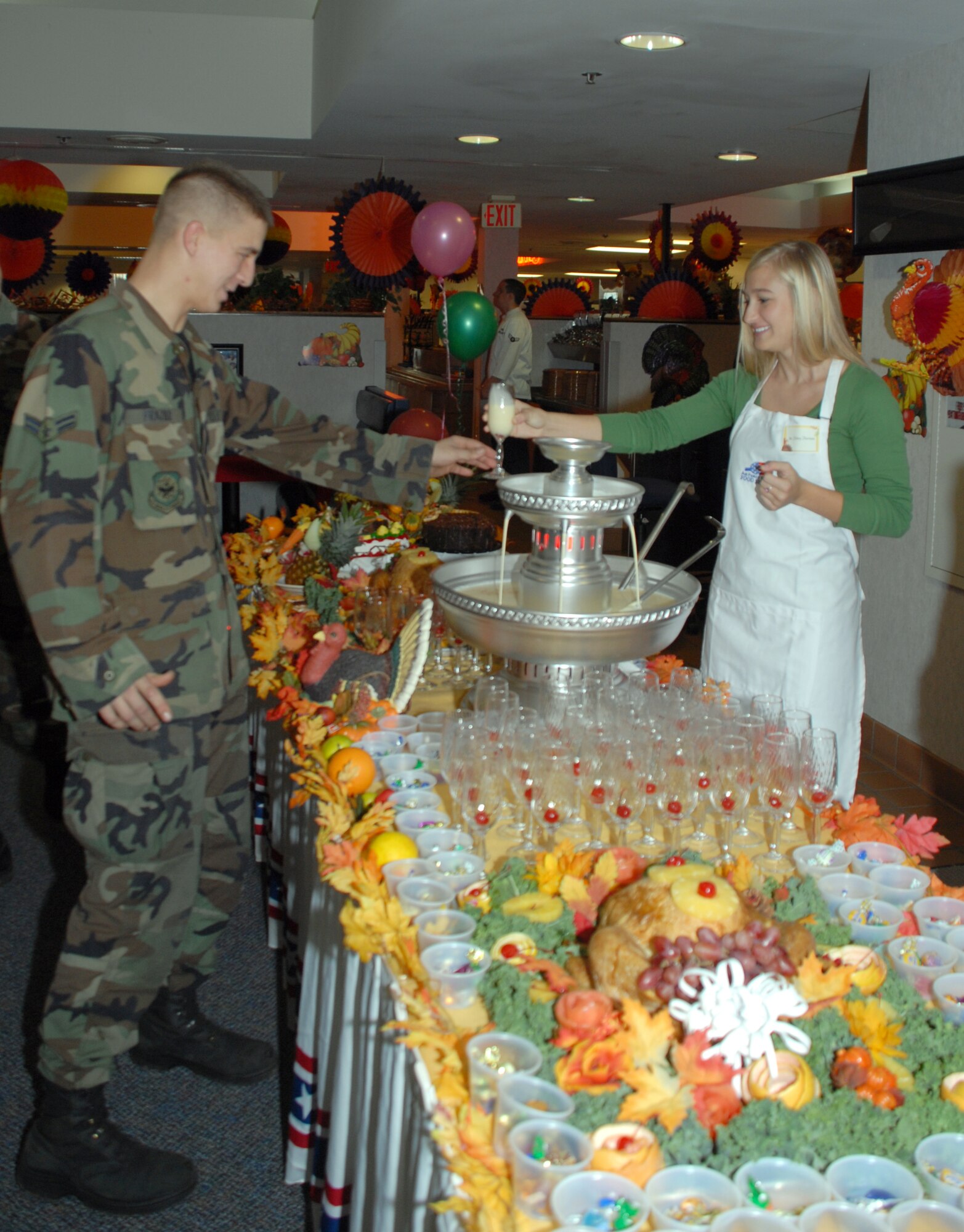 Airman 1st Class Randy Frazier, 436th Maintenance Squadron propulsion technician accepts a glass of egg nog from Hilary Harrison, daughter of Col. Steven Harrison, 436th Airlift Wing commander at a Thanksgiving lunch at the Patterson Dining Facility here Nov. 22. (U.S. Air Force photo/Tech. Sgt. Kevin Wallace)
