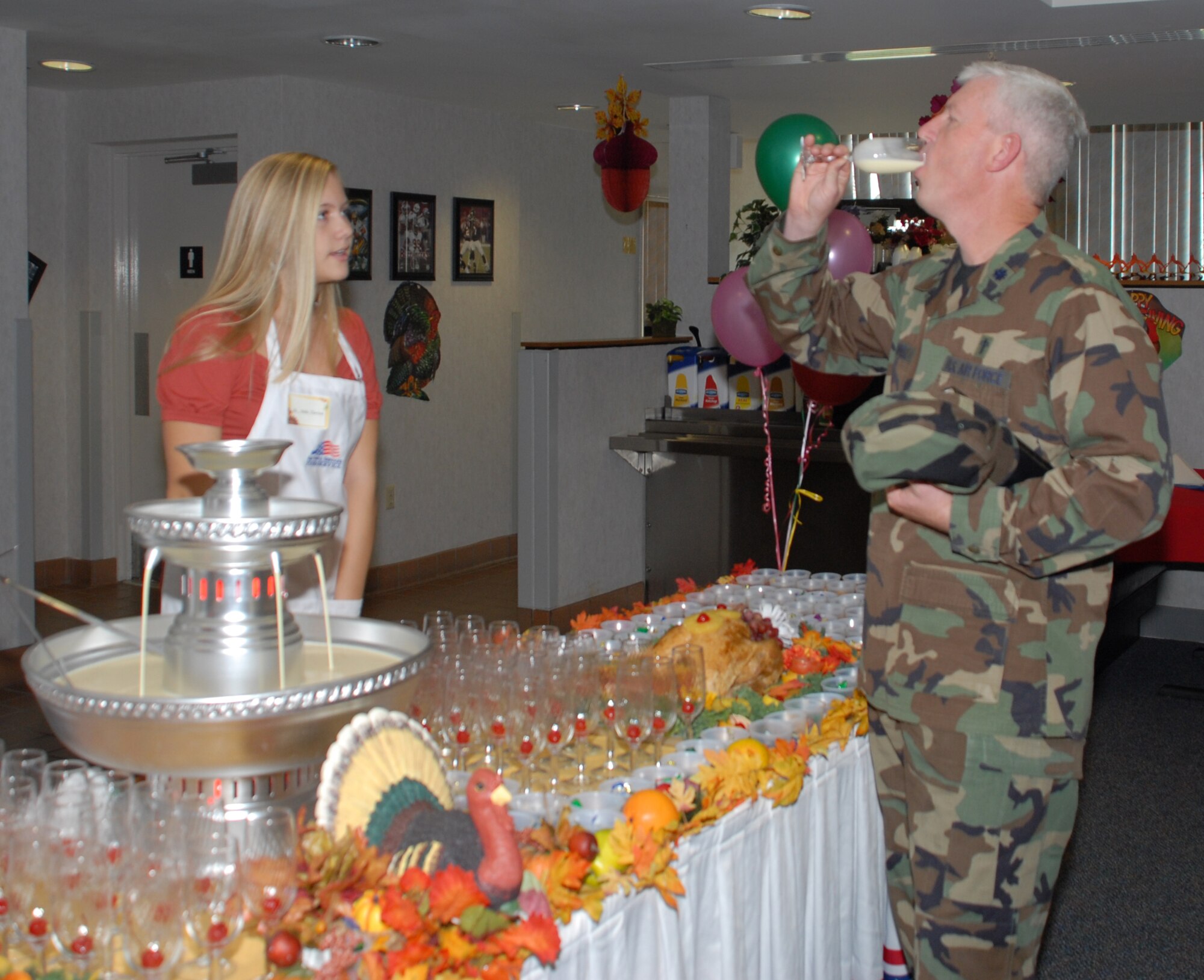 Chaplain (Lt. Col.) Ronald Harvell, 436th Airlift Wing chief chaplain, samples egg nog poured by Mollie Harrison, daughter of Col. Steven Harrison, 436th AW commander, at the lunch. (U.S. Air Force photo/Tech. Sgt. Kevin Wallace)
