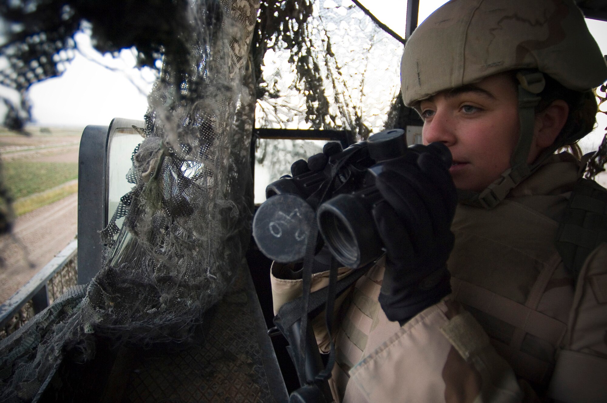 BALAD AIR BASE, Iraq -- Airman 1st Class Tara Krupke, a 332nd Expeditionary Security Forces Squadron response force team member, uses binoculars to study terrain off base here for enemy activity on Nov. 22. A vigilant Airman Krupke said she didn't believe enemy forces off base would take a break for the Thanksgiving holiday. She is deployed from Hill Air Force Base, Utah. (U.S. Air Force photo/Tech. Sgt. D. Clare)