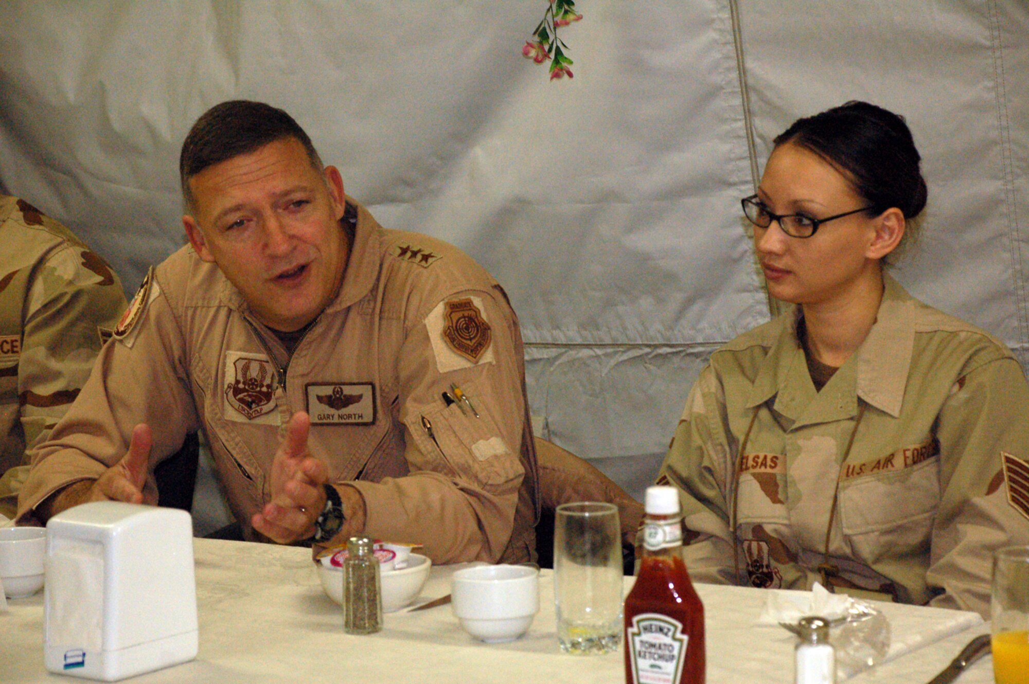 Tech. Sgt. Annalyn Elsas, 376th Personnel in Support of Contingency Operations, listens as Lt. Gen. Gary North, U.S. Central Command Air Forces Commander, talks with Manas Airmen at breakfast on Thanksgiving Day.  The general and Chief Master Sgt. Richard Small, USCENTAF command chief, are visiting Air Force bases in the AOR as the holiday season kicks off. (Air Force Photo by Senior Master Sgt. Stefan Alford)