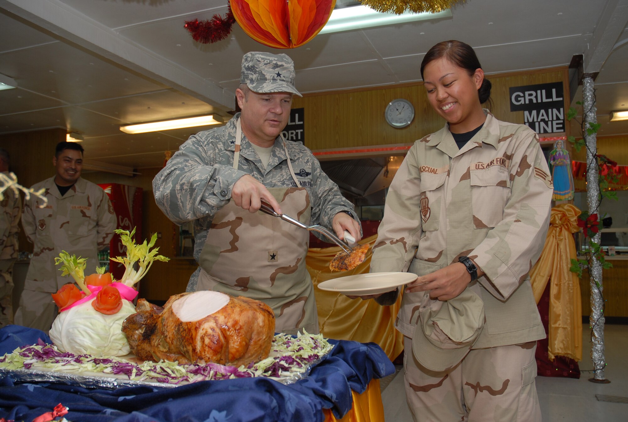 SOUTHWEST ASIA - Brig. Gen. Charlie Lyon, 379th Air Expeditionary Wing commander, serves the first cut from the Thanksgiving Day turkey to Senior Airman Nikki Pascaul at the Independence Dining Facility Nov. 22 at a Southwest Asia air base. Airman Pascaul is from  deployed here from Nellis Air Force Base, Nev., and her hometown is Honolulu, Hawaii. (U. S. Air Force photo/Staff Sgt. Douglas Olsen)
