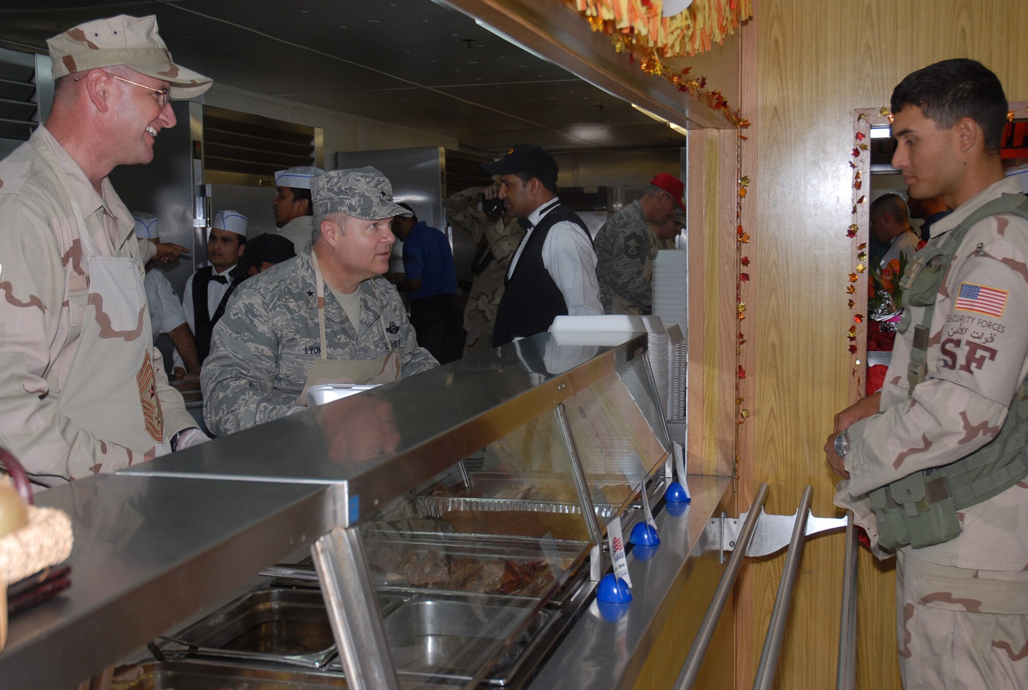 SOUTHWEST ASIA - Chief Master Sgt. Lloyd Hollen (left), 379th Air Expeditionary Wing command chief, and Brig. Gen. Charlie Lyon, 379th AEW commander, serve Thanksgiving dinner to Senior Airman Carlos Solorzano, 379th Expeditionary Security Forces Squadron, at the Independence Dining Facility Nov. 22 at a Southwest Asia air base. Airman Solorzano is deployed from Aviano Air Base, Italy. His hometown is Santa Clarita, Calif. (U. S. Air Force photo/Staff Sgt. Douglas Olsen)