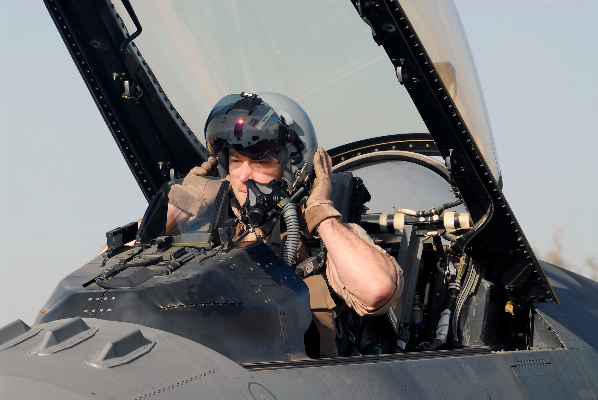 BALAD AIR BASE, Iraq -- Capt. Travis "Bandit" Keenan, a 22nd Expeditionary Fighter Squadron fighter pilot, dons his helmet in preparation for a combat mission here, Thanksgiving Day. Captain Keenan is deployed from Spangdahlem AB, Germany. (U.S. Air Force photo/Staff Sgt. Joshua Garcia)