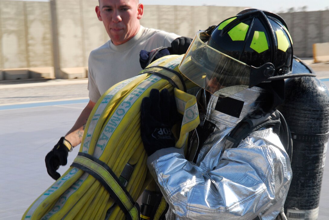 BALAD AIR BASE, Iraq -- Capt. Deborah Travis, 732nd Expeditionary Support Squadron director of operations, carries a fire hose during the Balad Firefighter Challenge here, Nov. 24. Participants in the competition competed in several different team events as well some solo challenges. Captain Travis is deployed from Langley Air Force Base, Va. (U.S. Air Force photo/Staff Sgt. Joshua Garcia)