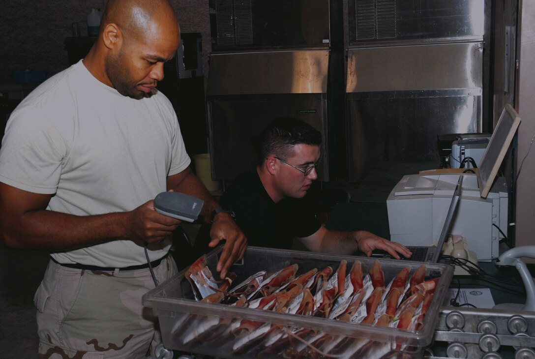 SPUTHWEST ASIA - Tech. Sgt. Joseph Pinkney (left) and Senior Airman Thomas Sullivan, 379th Expeditionary Medical Group Blood Transhipment Center, use the defense blood standard system to scan and track blodd products that are being shipped to Balad Air Base, Iraq. (U.S. Air Force photo/Staff Sgt. Doug Olsen)