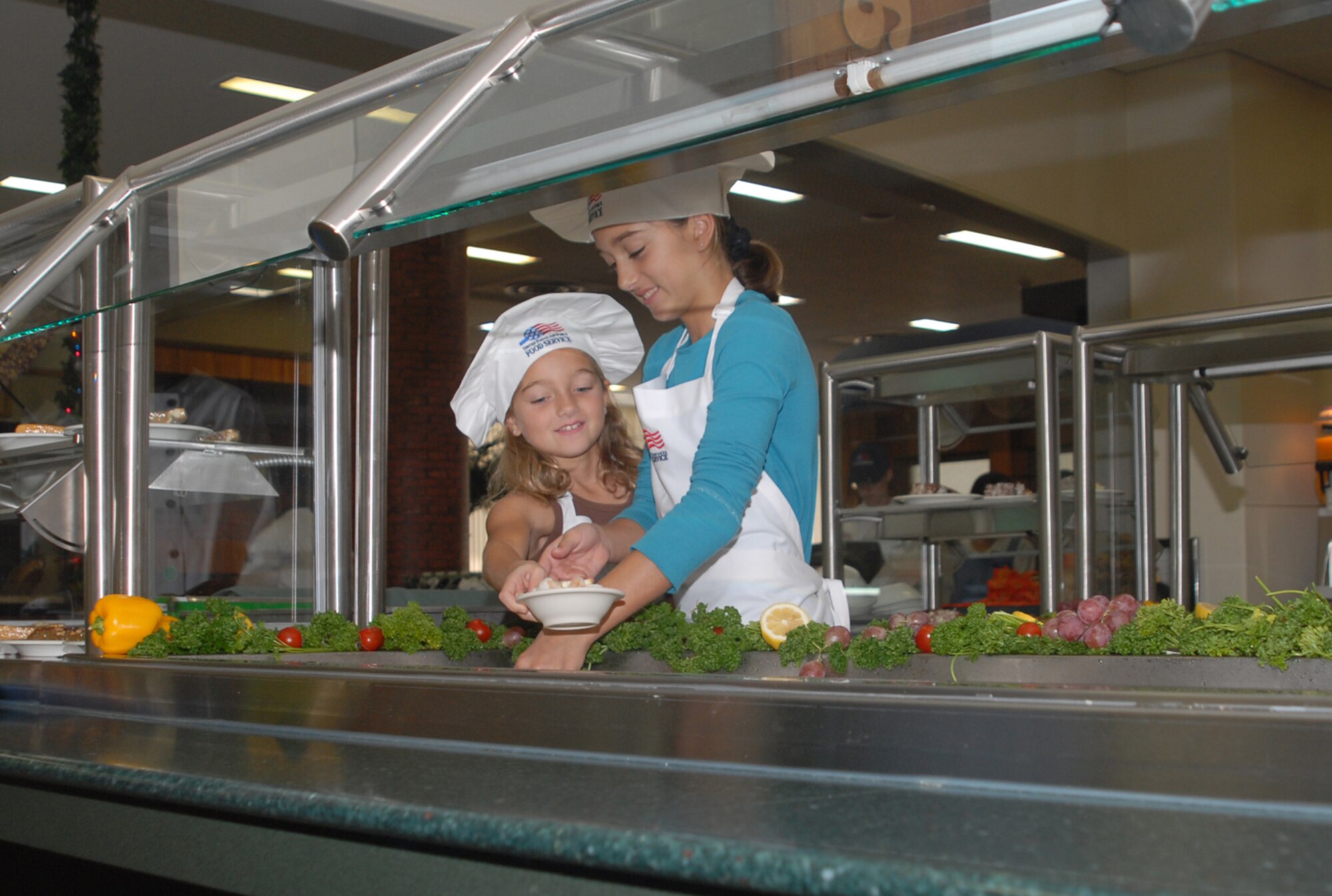 Hailey and Brooke Boutwell, dauthers of Lt. Col. Rick Boutwell, 44th Fighter Squadron commander, work at the salad bar during Thanksgiving dinner at the Kadena Air Base, Japan, Marshall Dining Facility, Nov. 22, 2007. Several commanders, senior NCOs and the girls helped serve lunch to dining facility patrons to thank them for their contributions to the mission. 