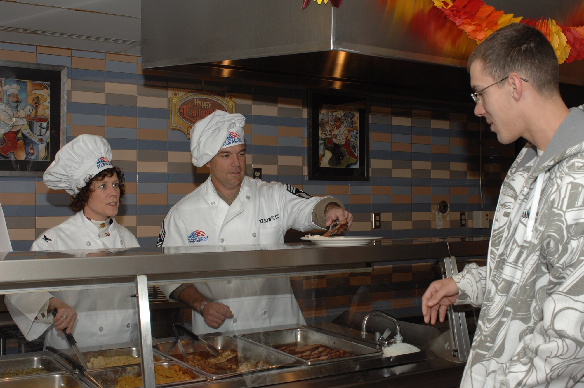 Col. Babette Lenfant, 27th Special Operations Mission Support Group commander, and 27th SOW Command Chief Master Sgt. Daniel Fischer, serve Thanksgiving dinner to an Airman at the Pecos Trail Dining Facility. Food during the meal was served by various commanders around base. (U.S. Air Force photo by Airman 1st Class Evelyn Chavez)