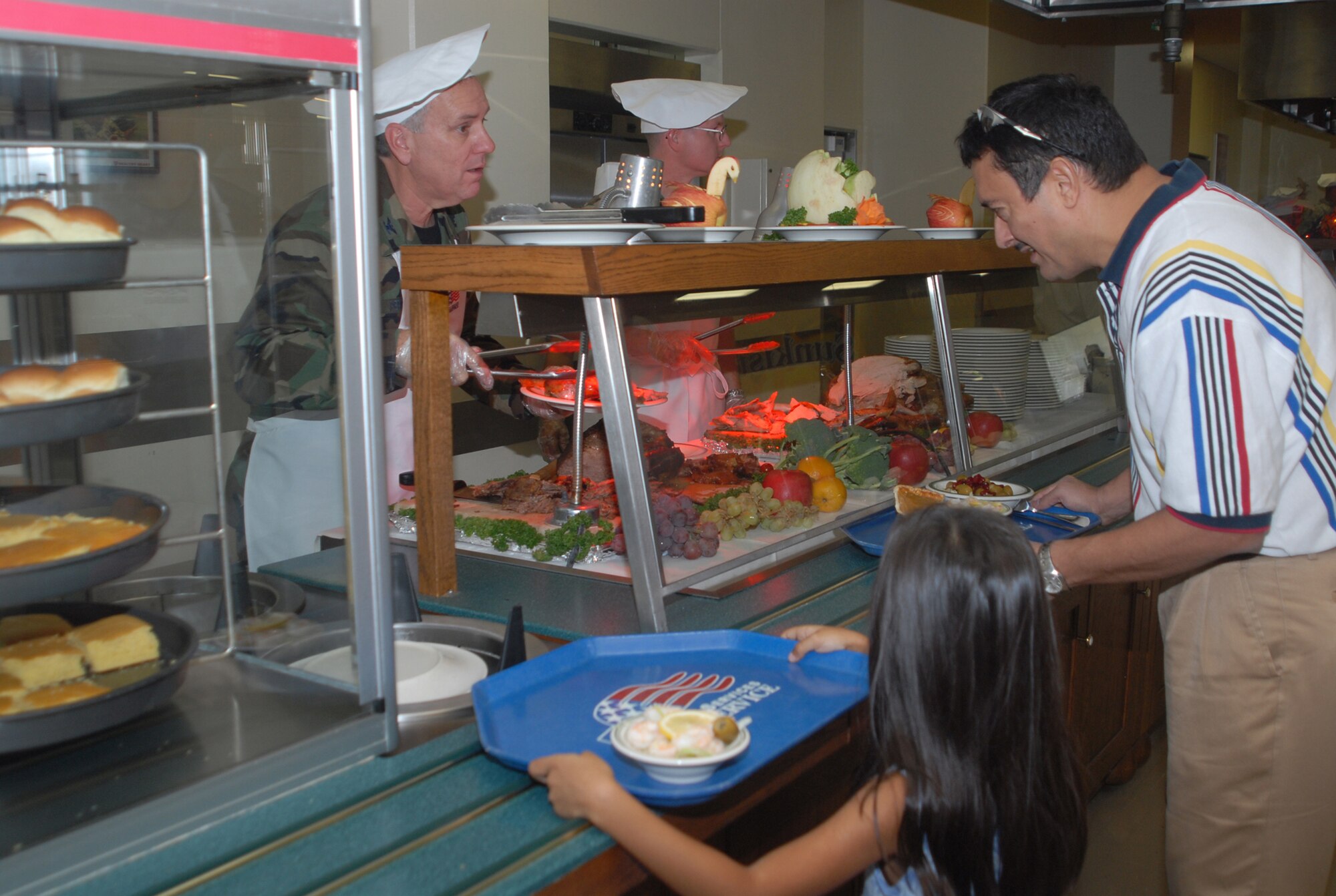 Col. Cliffton Perry, 18th Wing chaplain, serves Thanksgiving dinner to Athalee and Hector Reyes at the Kadena Air Base, Japan, Marshall Dining Facility, Nov. 22, 2007. Several commanders and senior NCOs served lunch to dining facility patrons to thank them for their contributions to the mission. 