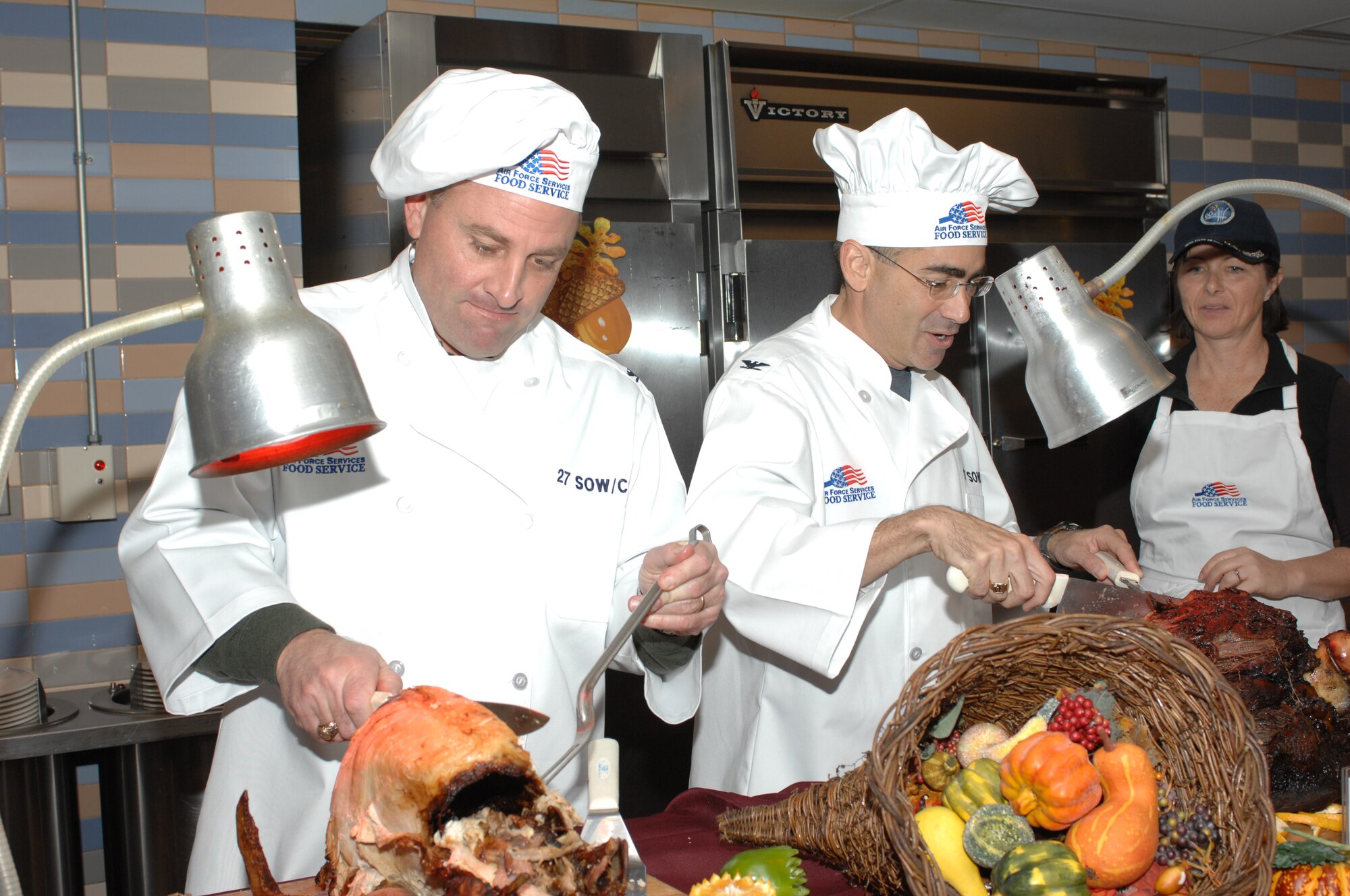 Col. Timothy Leahy, 27th Special Operations commander, and Col. Valentino Bagnani III, 27th SOW vice commander, carve up a turkey during the Pecos Trail Thanksgiving meal. Food during the meal was served by various commanders around base. (U.S. Air Force photo by Airman 1st Class Evelyn Chavez)