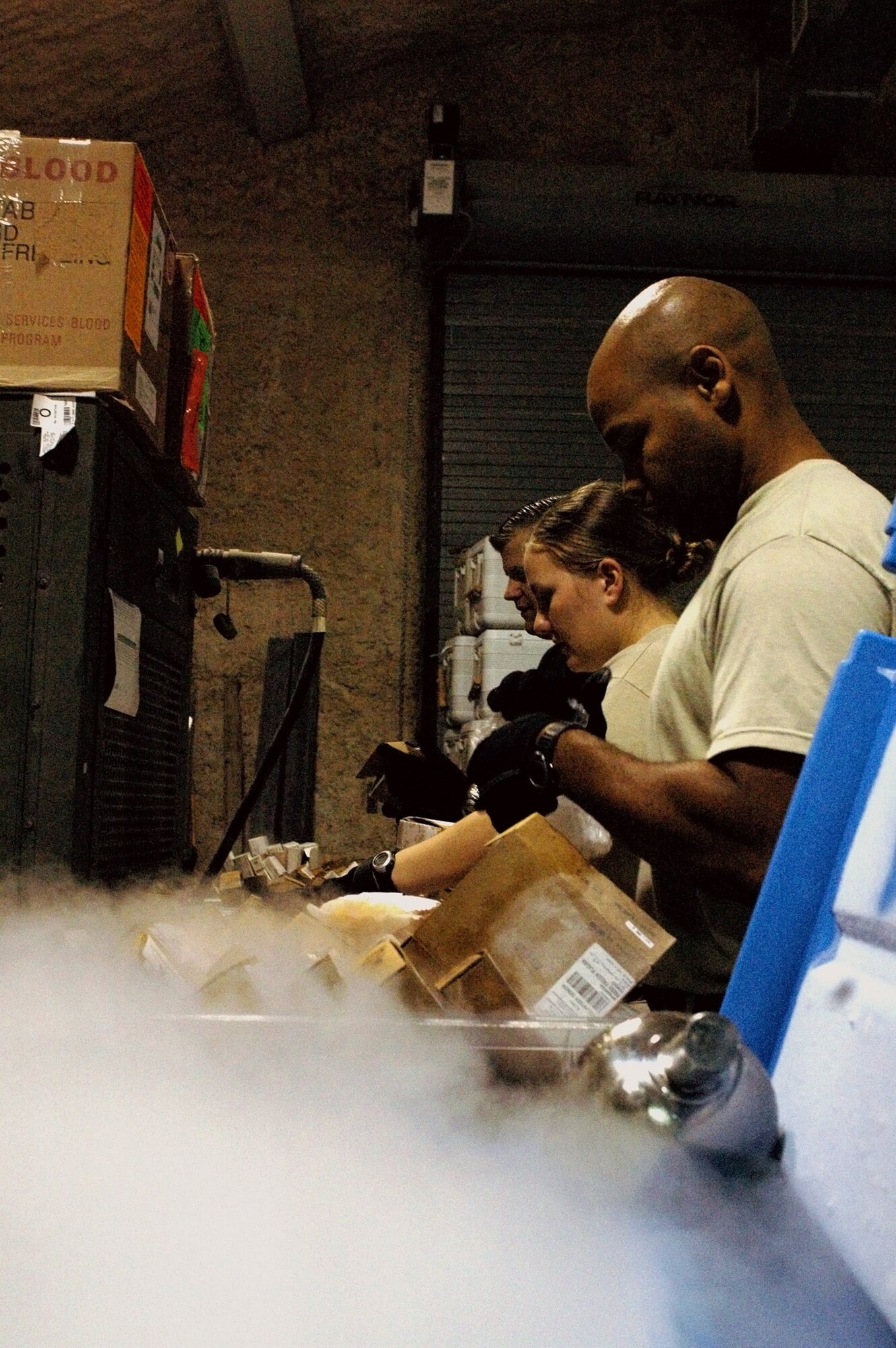 Tech. Sgt. Joseph Pinkney (from front), Senior Airmen Beth Gunn and Thomas Sullivan inspect and pack fresh frozen plasma Nov. 20 for a shipment from their Southwest Asia base to Balad Air Base, Iraq. Dry ice is used to keep the FFP frozen and prevent spoilage. Sergeant Pinkney and Airmen Gunn and Sullivan are with the 379th Expeditionary Medical Group's blood transshipment center and are deployed from Langley Air Force Base, Va. (U.S. Air Force photo/Staff Sgt. Jason Barebo) 