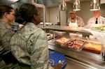 The 37th Training Wing command chief master sergeant and the director of staff, Chief Master Sgt. Dwayne Hopkins, right, and Col. Stevenson Ray, respectively, serve a Thanksgiving meal to trainees at the 322nd Training Squadron on Thanksgiving Day. Chief Hopkins and Colonel Ray were two of more than 80 members of Team Lackland who worked shifts in eight open dining facilities on Thanksgiving. (USAF photo by Robbin Cresswell)
