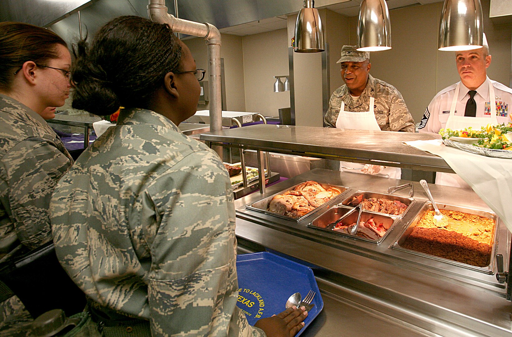 The 37th Training Wing command chief master sergeant and the director of staff, Chief Master Sgt. Dwayne Hopkins, right, and Col. Stevenson Ray, respectively, serve a Thanksgiving meal to trainees at the 322nd Training Squadron on Thanksgiving Day. Chief Hopkins and Colonel Ray were two of more than 80 members of Team Lackland who worked shifts in eight open dining facilities on Thanksgiving. (USAF photo by Robbin Cresswell)