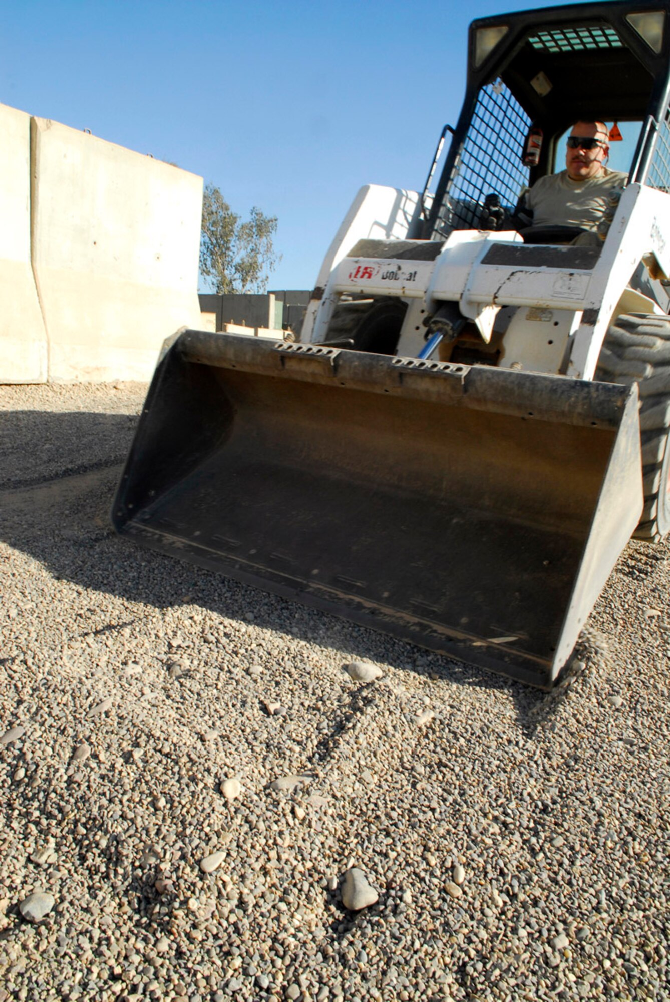 Master Sgt. James MacDonald levels gravel using a skid loader Nov. 25 at Balad Air Base, Iraq. With the rainy season approaching, the gravel will allow members of 727th Expeditionary Air Control Squadron to walk through the site without their boots collecting too much mud. Sergeant McDonald, the 727th EACS Aerospace Ground Equipment Flight noncommissioned officer in charge, is deployed from Mountain Home Air Force Base, Idaho. (U.S. Air Force photo/Staff Sgt. Joshua Garcia) 
