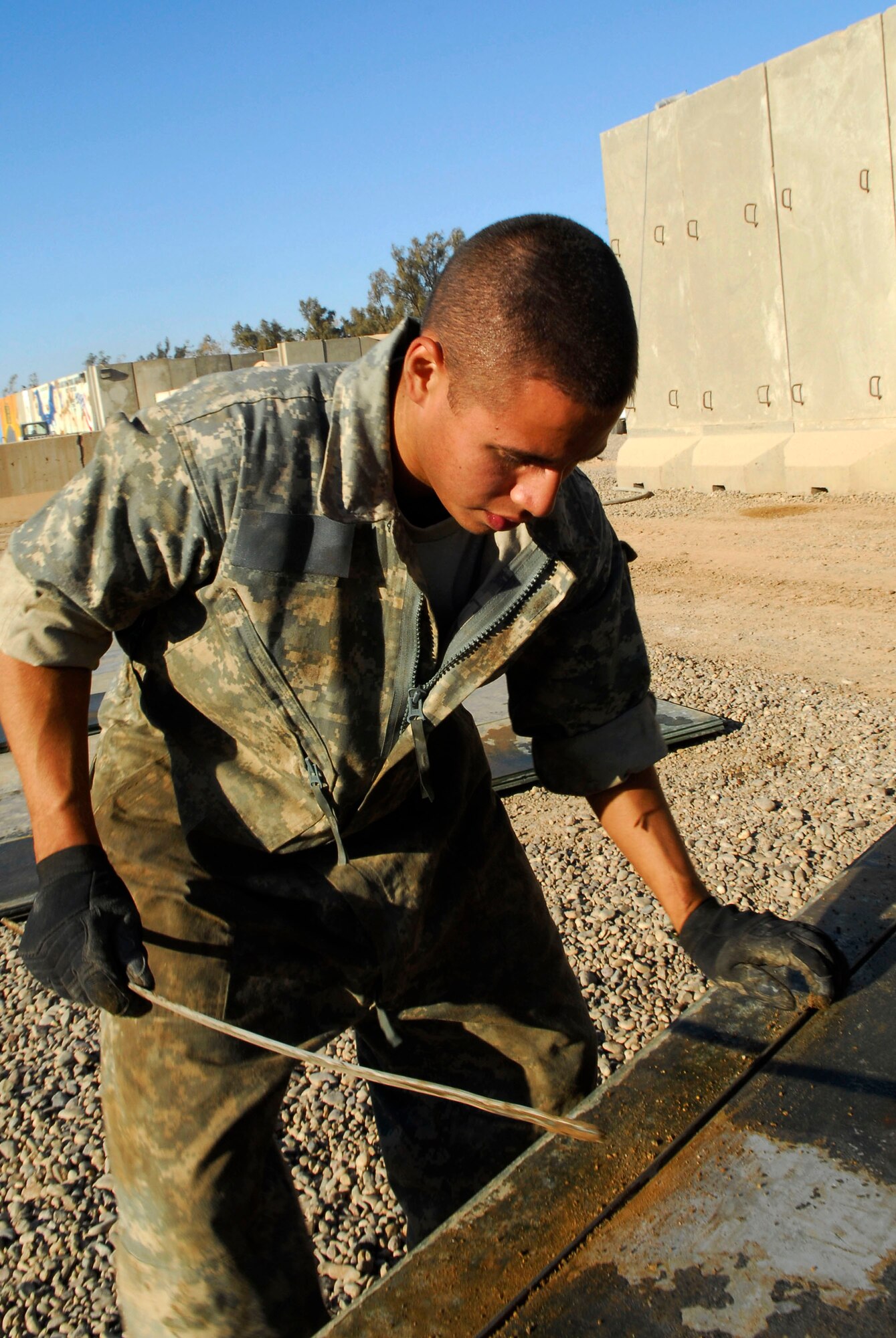 Airman 1st Class Joshua Vasquez cleans grooves on a floor panel for the new vehicle maintenance overhang Nov. 25 at Balad Air Base, Iraq. During Iraq's rainy season, mud can impact the Air Force's mission. The new shelter will allow vehicle maintainers to accomplish their mission in any type of weather. Airman Vasquez, a 727th Expeditionary Aircraft Squadron vehicle maintainer, is deployed from Mountain Home Air Force Base, Idaho. (U.S. Air Force photo/Staff Sgt. Joshua Garcia) 
