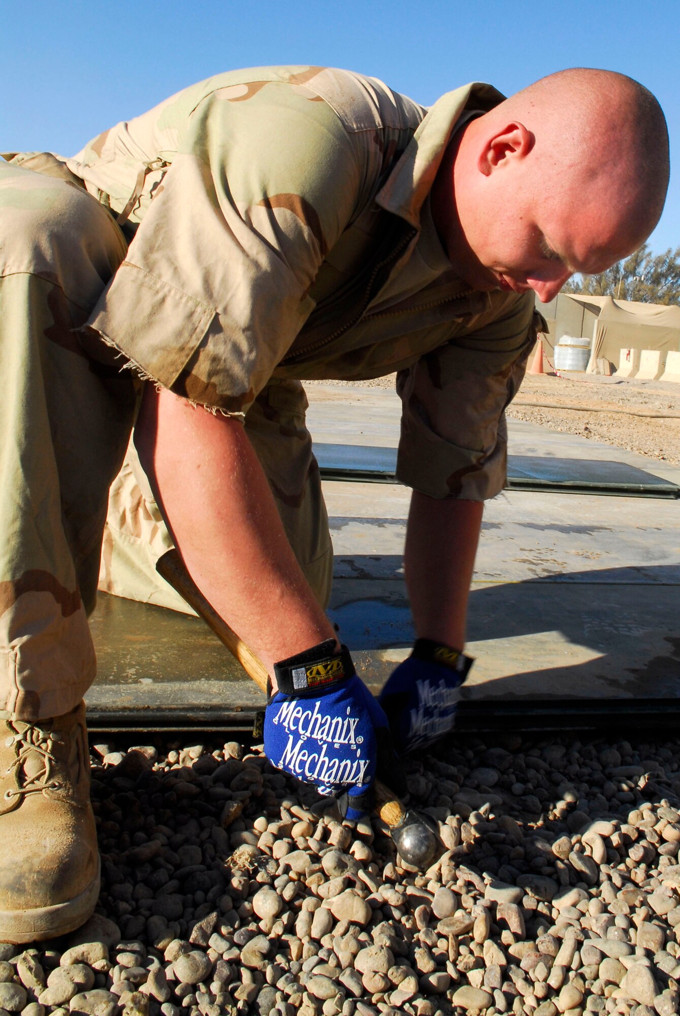 Senior Airman Kevin Marshall connects two pieces of matting for the floor on the new vehicle maintenance overhang Nov. 25 at Balad Air Base, Iraq. The new overhang, which will be twice the size of its predecessor, will cover a leveled-gravel surface preventing water pockets from forming underneath the matting during the rainy season. Airman Marshall, a 727th Expeditionary Air Control Squadron vehicle maintainer, is deployed from Mountain Home Air Force Base, Idaho. (U.S. Air Force photo/Staff Sgt. Joshua Garcia) 
