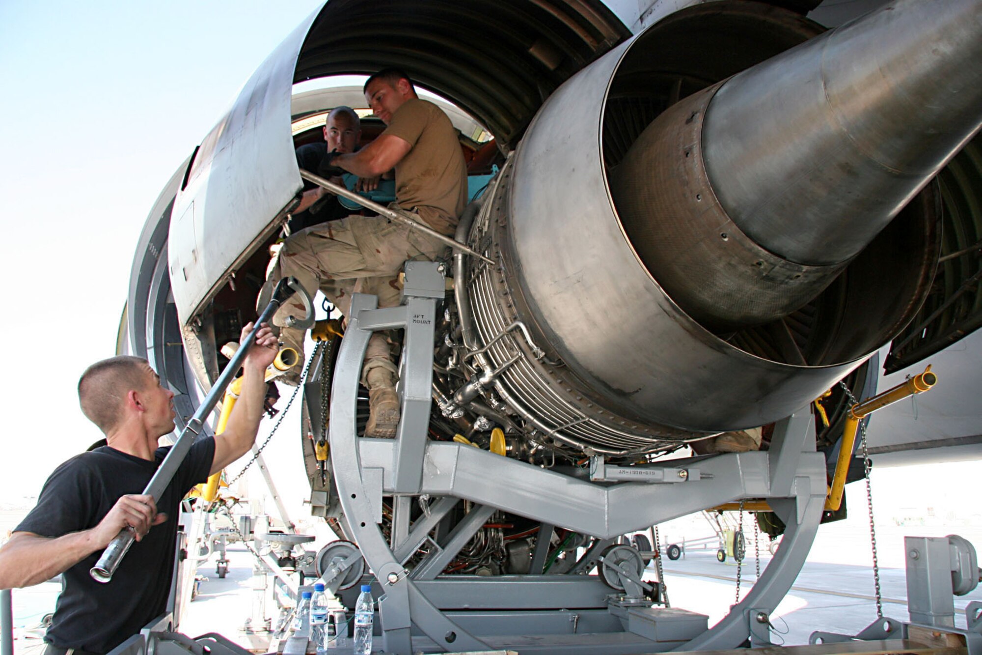 KC-10 Crew Chief Staff Sgt. Kevin Brown, hands Staff Sgt. Jamie Sherwood, KC-10 engine mechanic and Staff Sgt. Joseph Dodson, crew chief, a torque wrench to help install the KC-10 Engine.  This engine change took two days and tested the mechanical ability of the Airmen of the 380th Expeditionary Aircraft Maintenance Squadron after the engine hoist failed. They used alternative methods to raise and install the engine. Mechanical ingenuity assisted Airmen from the sheet metal and quality assurance shops who worked together along side the crew chiefs and engine mechanics to install the engine  in this expeditionary environment where recourses are sometimes limited.  (U.S. Air Force Photo/Master Sgt. Ruby Zarzyczny)