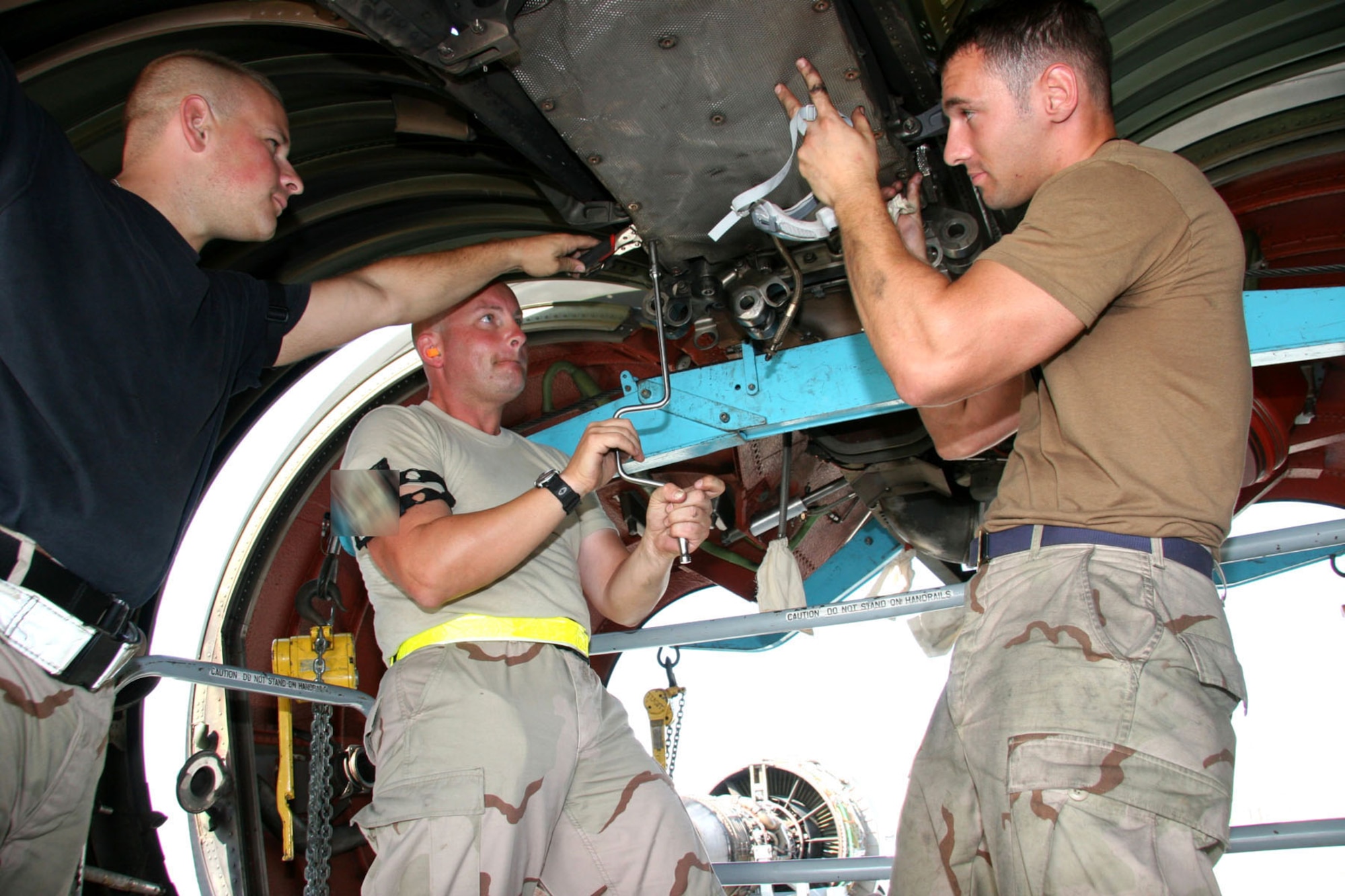After removing the number one engine that had turban blade damage as a result of normal wear and tear, Tech. Sgt. Art Hall, engine mechanic (left), Tech. Sgt. Rick Baugnet, quality assurance, and Staff Sgt. Jamie Sherwood remove the engine mount bolt and prepare to install the new engine.  (U.S. Air Force Photo/Master Sgt. Ruby Zarzyczny)