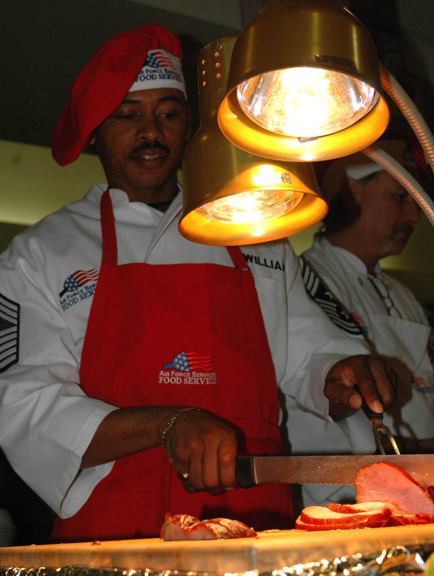 Chief Master Sgt. Michael Williams, 60th Air Mobility Wing command chief, serves ham during the Thanksgiving Day meal at the Sierra Inn Dining Facility. (U.S. Air Force photo/Senior Airman Shaun Emery)