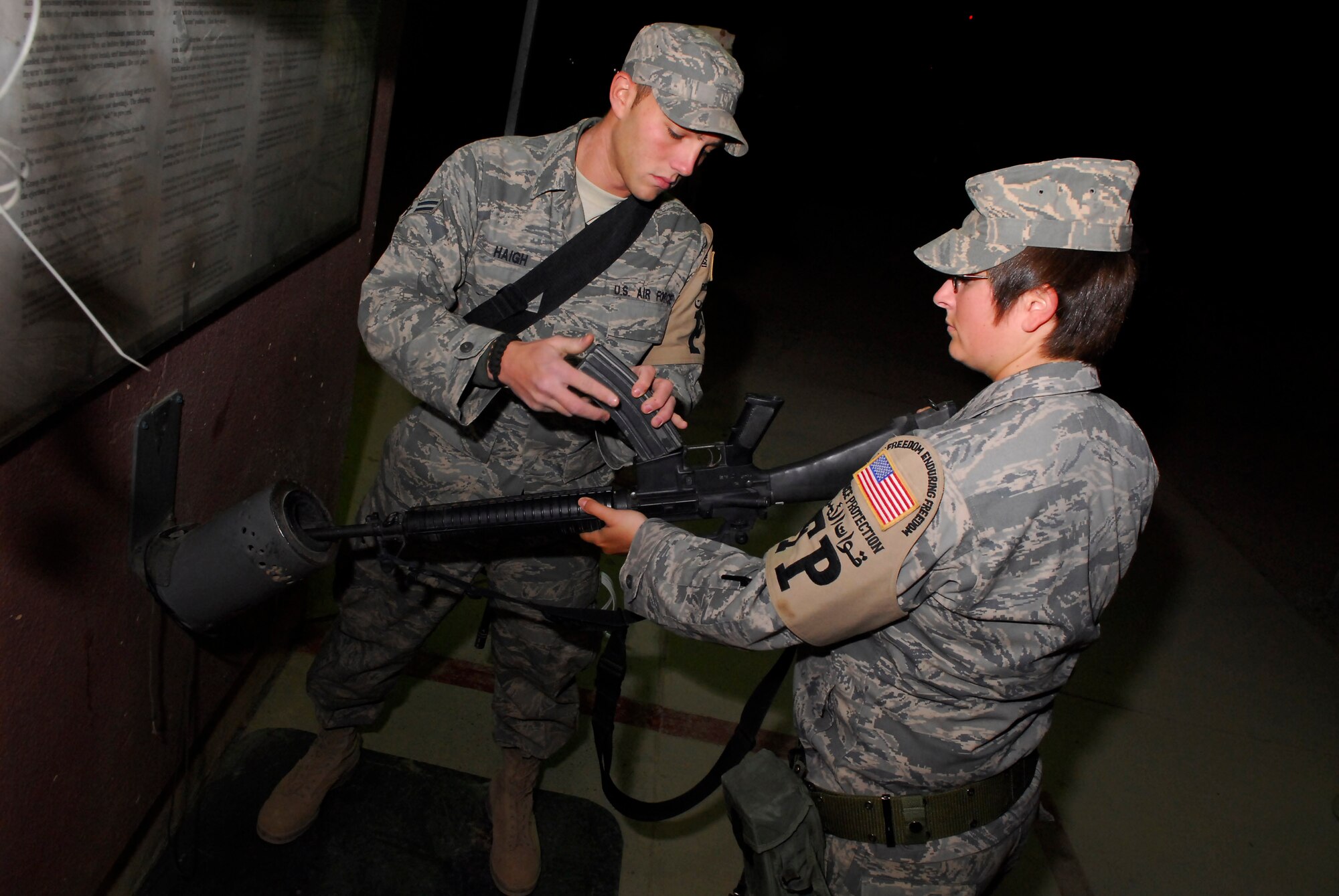 BALAD AIR BASE, Iraq -- Airman 1st Class William Haigh helps Staff Sgt. Karen White load her M-16A2 rifle before duty here. Airman Haigh and Sergeant White are 332nd Expeditionary Security Forces Squadron escorts. They are responsible for ensuring the safety of Air Force property and personnel on base. Both are deployed from Hurlburt Field, Fla. (U.S. Air Force photo/Staff Sgt. Joshua Garcia)