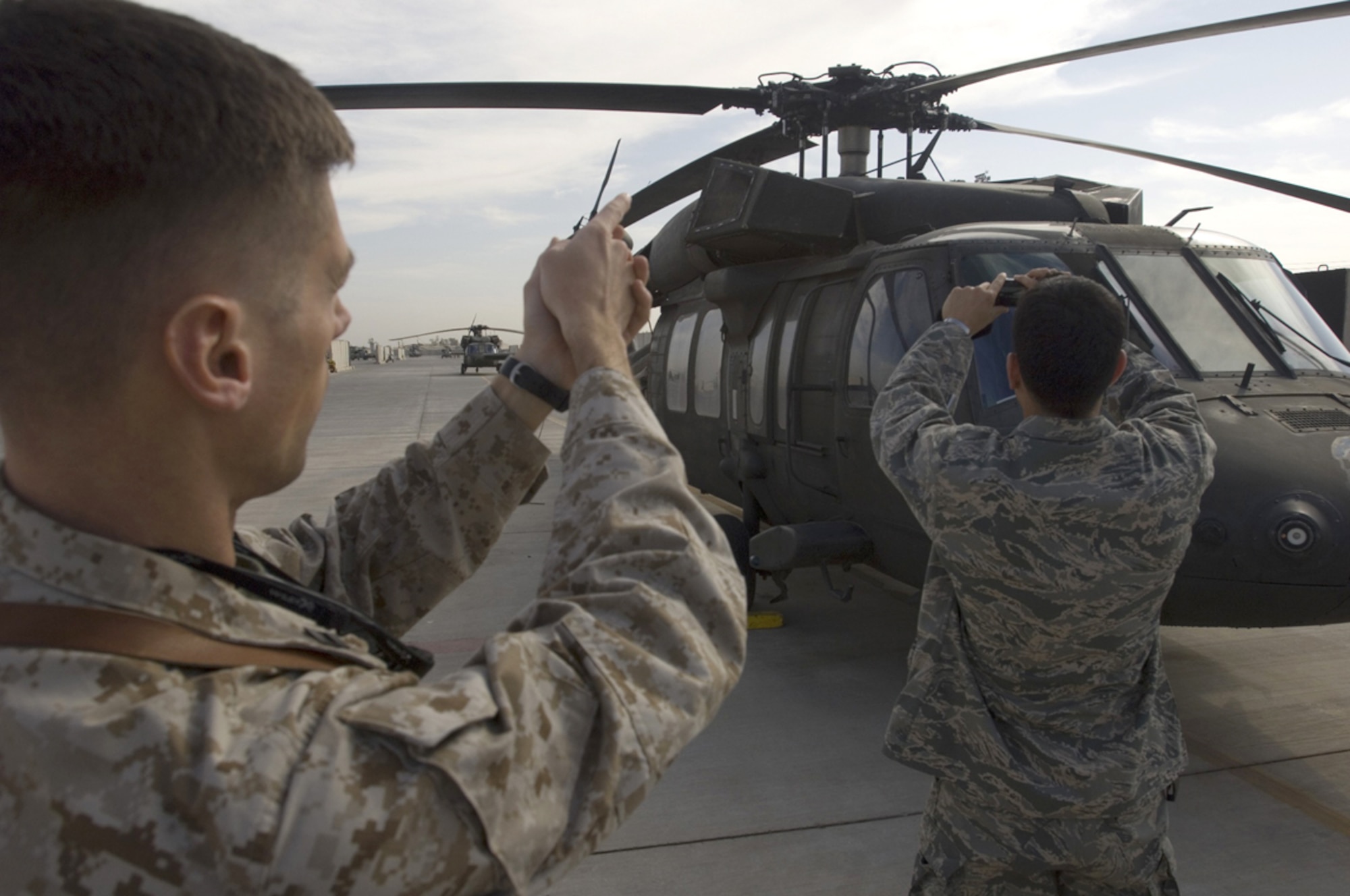 BALAD AIR BASE, Iraq -- Navy Lt. Shawn Denihan, Joint Combat Assessment Team officer-in-charge, simulates the likely angle of attack the enemy used to fire upon an Army MH-60 Black Hawk helicopter, as Capt. Francis Marino, a JCAT assessor takes photographs. By recreating the enemy attack, the team is able to aid intelligence efforts in Iraq and help leaders make informed decisions about operations in the area of responsibility. Captain Marino is deployed from Wright-Patterson Air Force Base, Ohio. Lt. Denihan is a member of the Navy Reserve deployed from Naval Air Station Pawtuxet River, Md. (U.S. Air Force photo/Tech. Sgt. D. Clare)