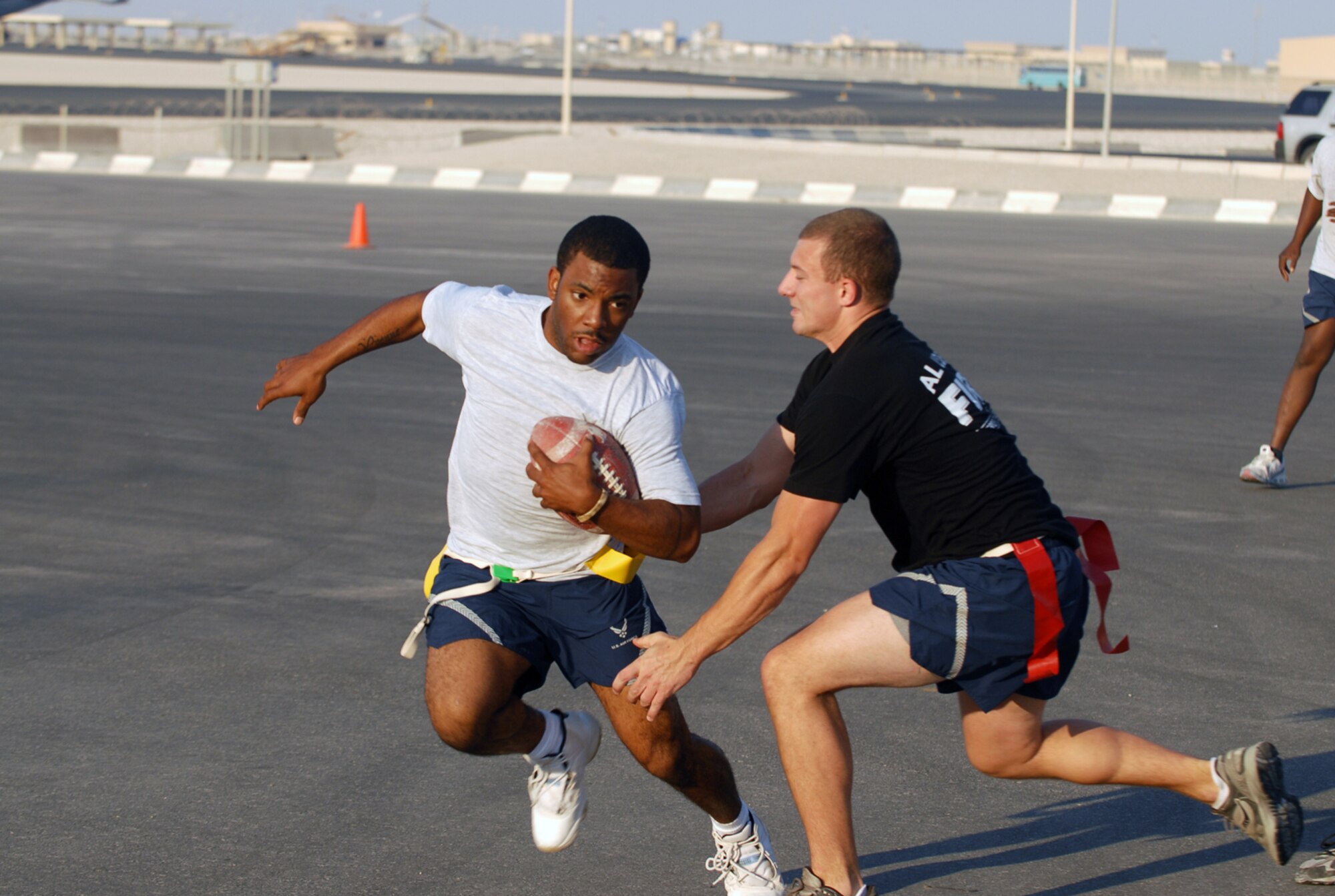 SOUTHWEST ASIA - Part of the Thanksgiving Day festivities at a Southwest Asia air base included a flag football game between the 379th Expeditionary Security Forces Squadron  law enforcers and the 379th Expeditionary Civil Engineer Squadron fire fighters. Airman 1st Class Artie Johnson, 379th ESFS, swerves to avoid Senior Airman Shawn Reinecke, 379th ECES. (U. S. Air Force photo/Staff Sgt. Douglas Olsen)


