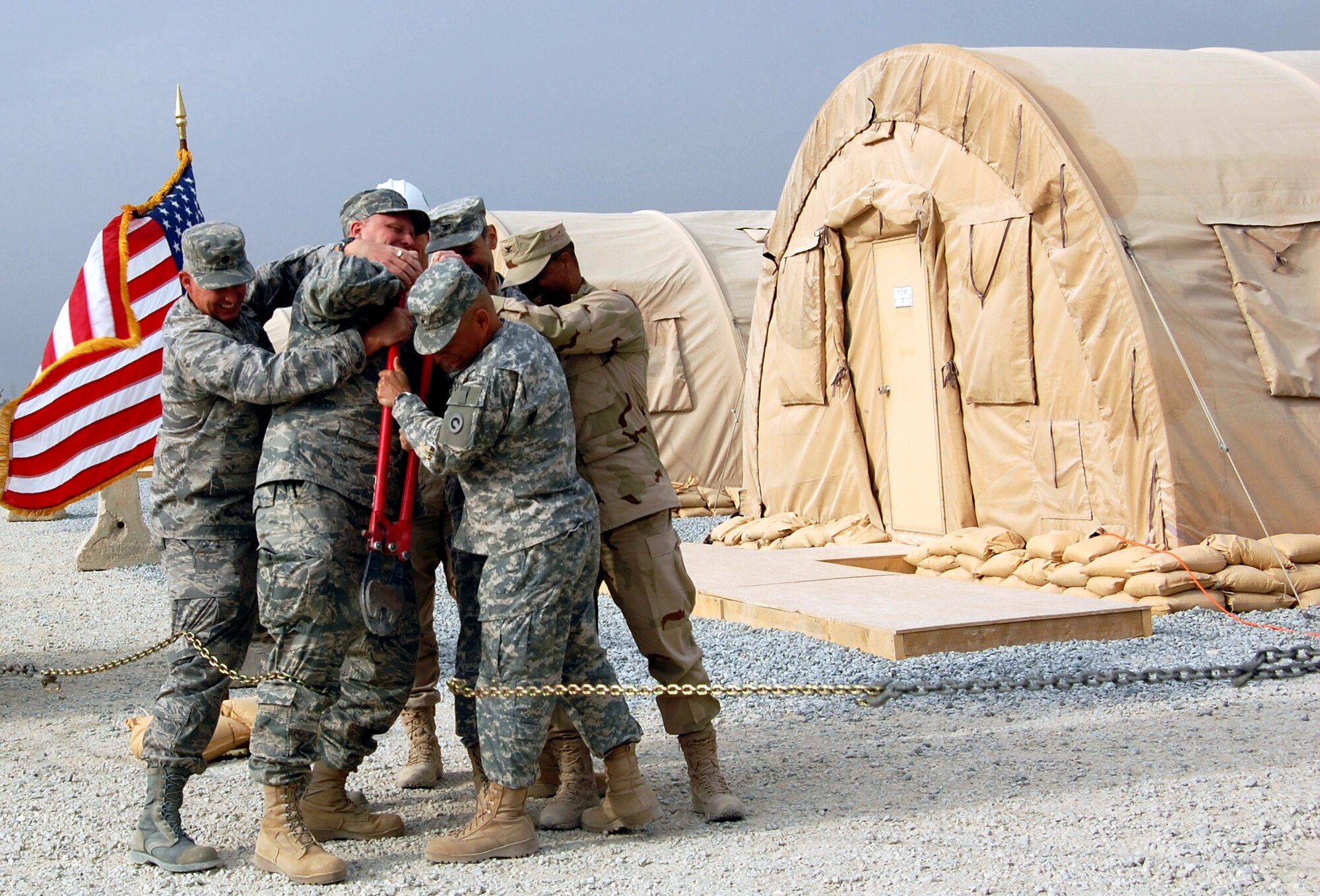 A group of commanders work together to cut a chain for the grand opening of the new convoy support center Nov. 24 in Southwest Asia. The new eight-tent center consolidates all of the Air Force convoy support functions into one area. (U.S. Air Force photo/Staff Sgt. Phillip Butterfield) 