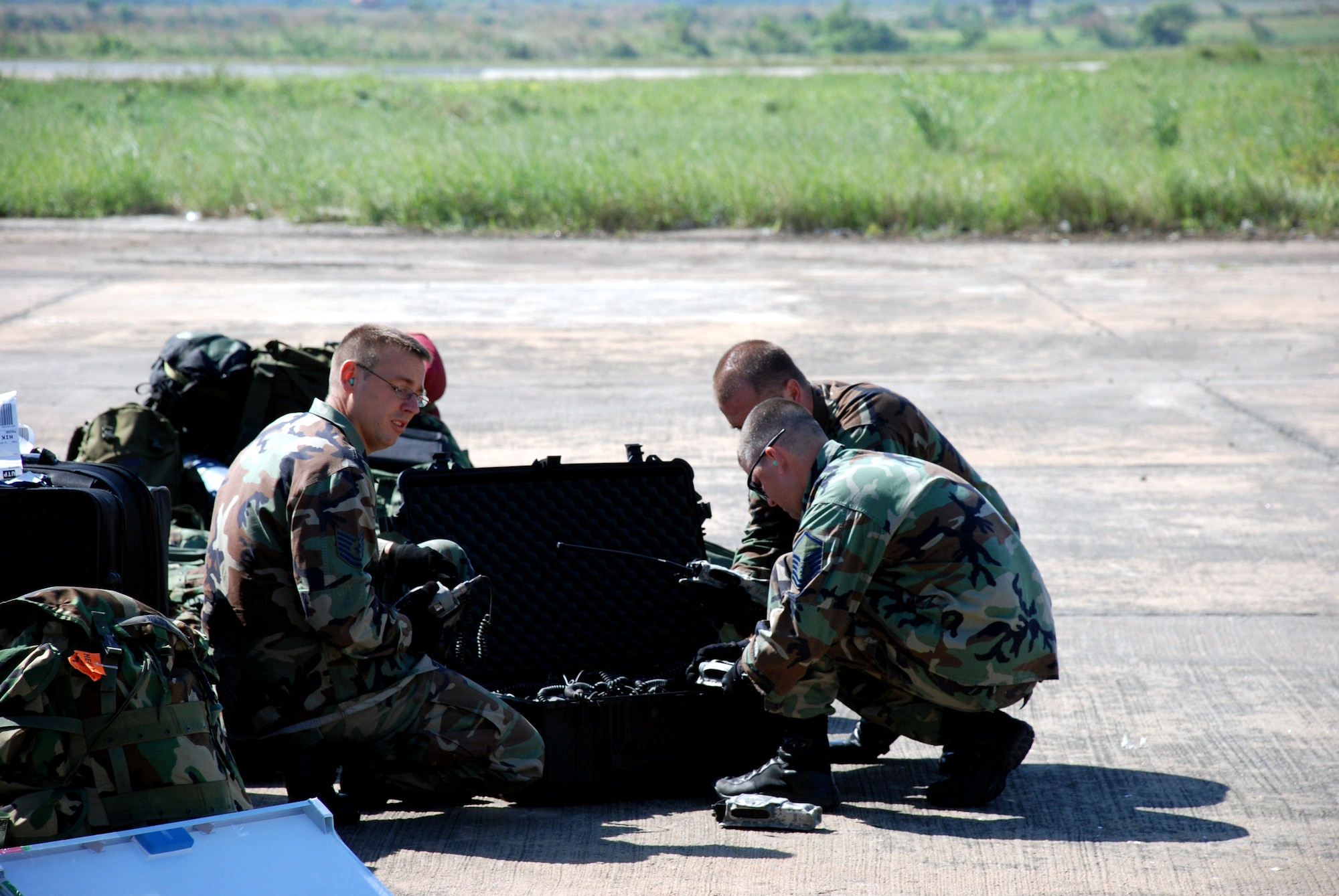 Three Airmen work to establish a communications system Nov. 26 at Zia International Airport in Dhaka, Bangladesh. The Airmen are part of a 37-person team from the 36th Contingency Response Group at Andersen Air Force Base, Guam, and are tasked to establish relief supply transload operations in the wake of a Nov. 15 tropical cyclone that devastated much of the southern part of the country.The 13th Air Force-led mission employed a C-17 Globemaster III from Hickam AFB, Hawaii, to bring the Airmen to Bangladesh. (U.S. Air Force photo/1st. Lt. Michael Boyer) 
