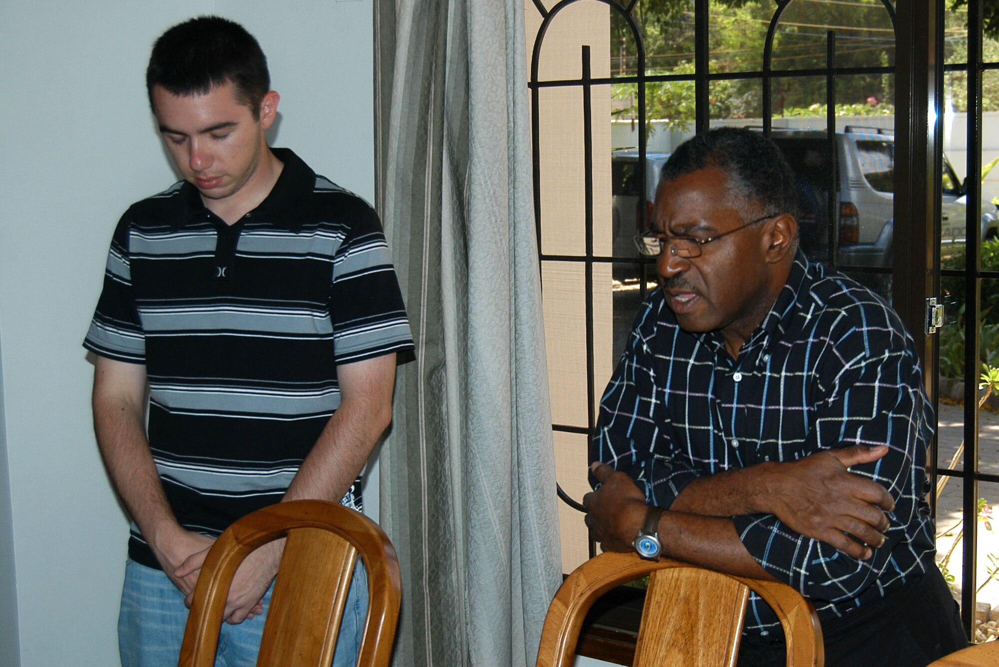 Ch. (Lt. Col.) Lawrence F. Keith (right) says grace while Army Spc. Michael R. Johnston bows his head before eating a Thanksgiving meal at the house of a servicemember assigned to the U.S. Embassy in Tanzania. Chaplin Keith, a Blytheville, Ark., native, is the Combined Joint Task Force-Horn of Africa Religious Affairs deputy director, and Specialist Johnston, a Tulsa, Okla., native, is a civil affairs specialist assigned to Civil Affairs Team 11 of C Company, 486th Civil Affairs Battalion. (U.S. Air Force photo/Staff Sgt. Jennifer Redente)