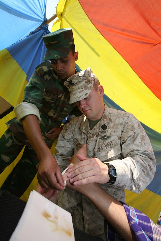 A Bangladeshi soldier and Petty Officer 3rd Class Samuel D. Schaeffer, a hospital corpsman with the 22nd Marine Expeditionary Unit (Special Operations Capable), render medical aid to a victim of Tropical Cyclone Sidr, South Khali, Bangladesh, Nov. 28, 2007. Marines and Sailors of the USS Kearsarge (LHD 3) and the embarked elements of the 22nd MEU (SOC) arrived off the coast of Bangladesh Nov. 23 to support ongoing relief efforts at the request of the Bangladesh Government. (Official U.S. Marine Corps photo by Cpl. Peter R. Miller)