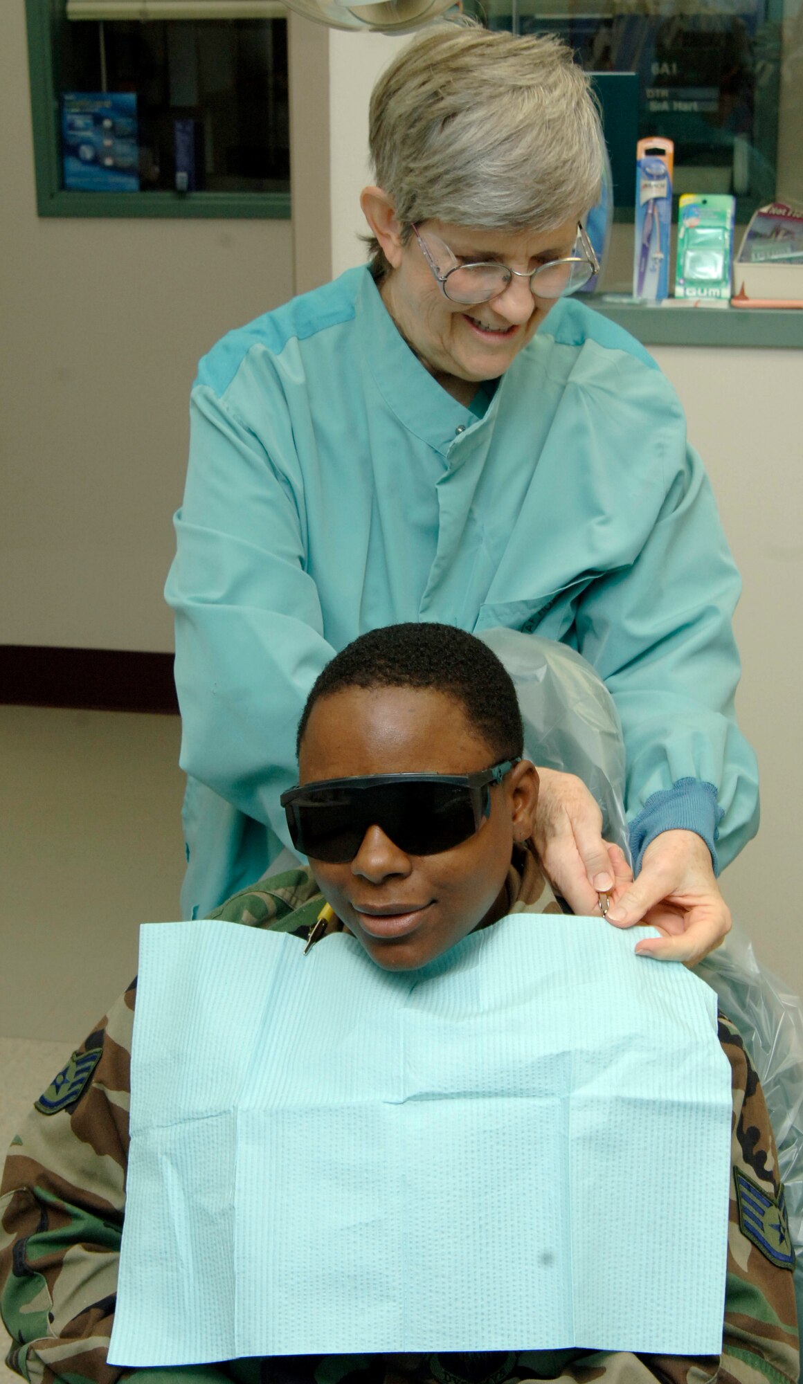 MCCONNELL AIR FORCE BASE, Kan. -- Carol Cowart, 22nd Aero Medical Dental Squadron, places a bib on Staff Sergeant Kahlila Mutidi, 22nd Civil Engineer Squadron, at the dental clinic Nov. 21.  Due to manning, the dental clinic can only accept active duty personnel. (Photo by Airman 1st Class Roy Lynch III) 