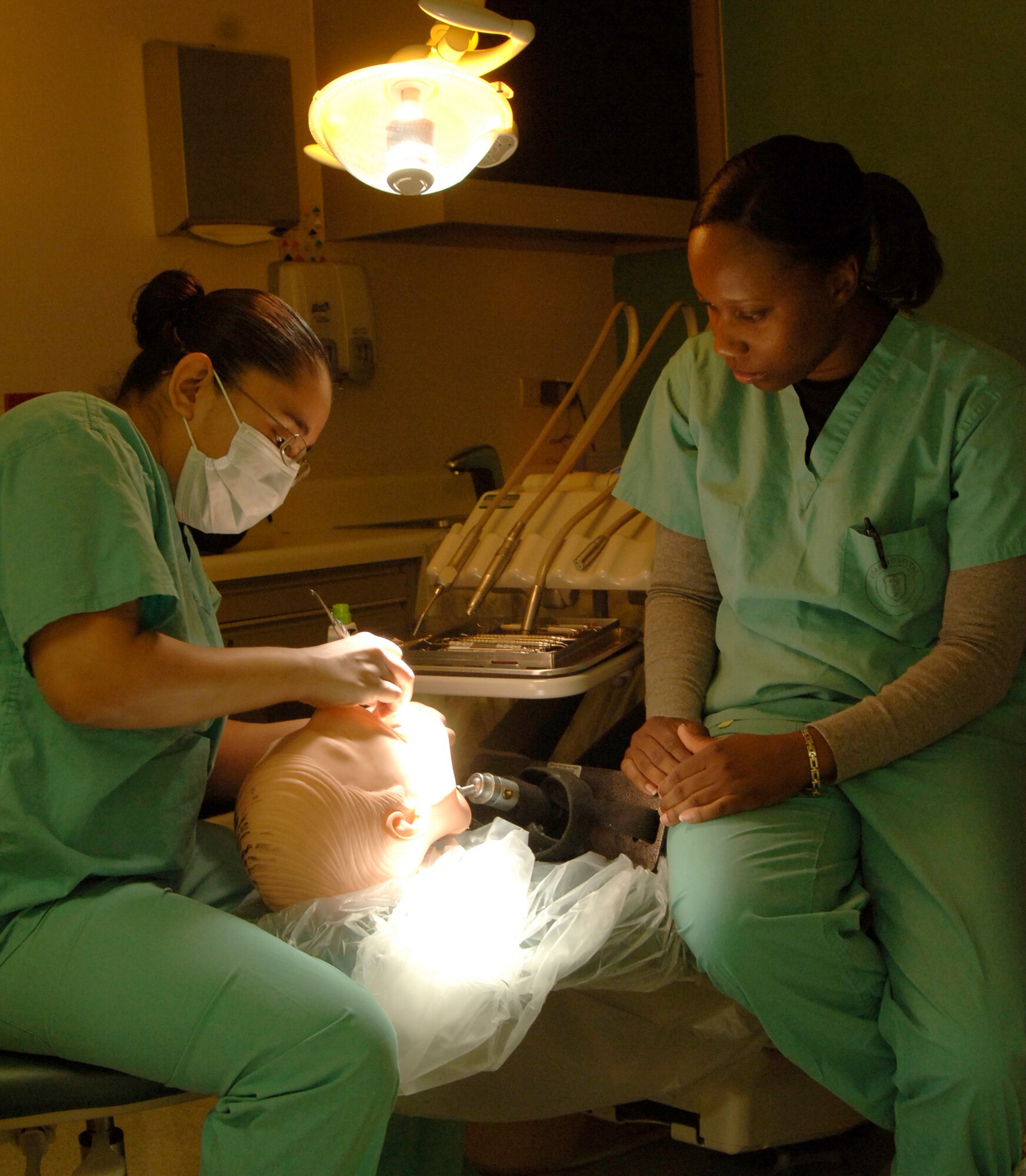 MCCONNELL AIR FORCE BASE, Kan. -- Staff Sgt. Aretha Sterling, right, 22nd Aero Medical Dental Squadron, trains Airman 1st Class Crystal Ballesteros, 22nd Aero Medical Dental Squadron, on cleaning teeth on a training mannequin at the dental clinic Nov. 21. All dental assistants receive 11 weeks of special education in addition to military upgrade training. (Photo by Tech. Sgt. Chyrece Campbell)