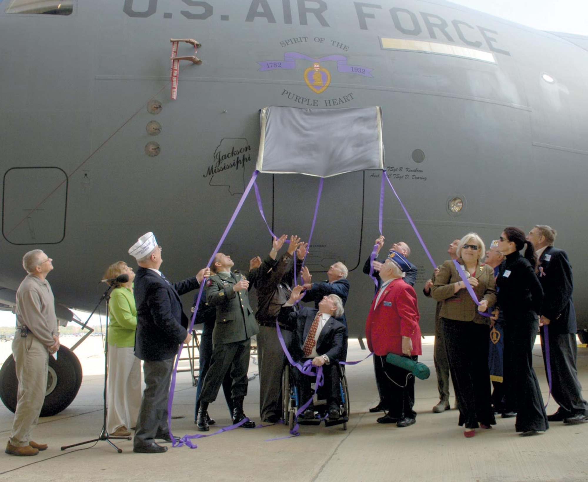 Distinguished guests pull down the curtain to unveil the Purple Heart insignia on a C-17 assigned to the Mississippi Air National Guard. The Nov. 20 ceremony in Jackson, Miss. also honored the 75th Anniversary of the current Purple Heart decoration, by designating a C-17 Globemaster III as the "Spirit of the Purple Heart." (US Air Force/A1C Renae Kleckner)