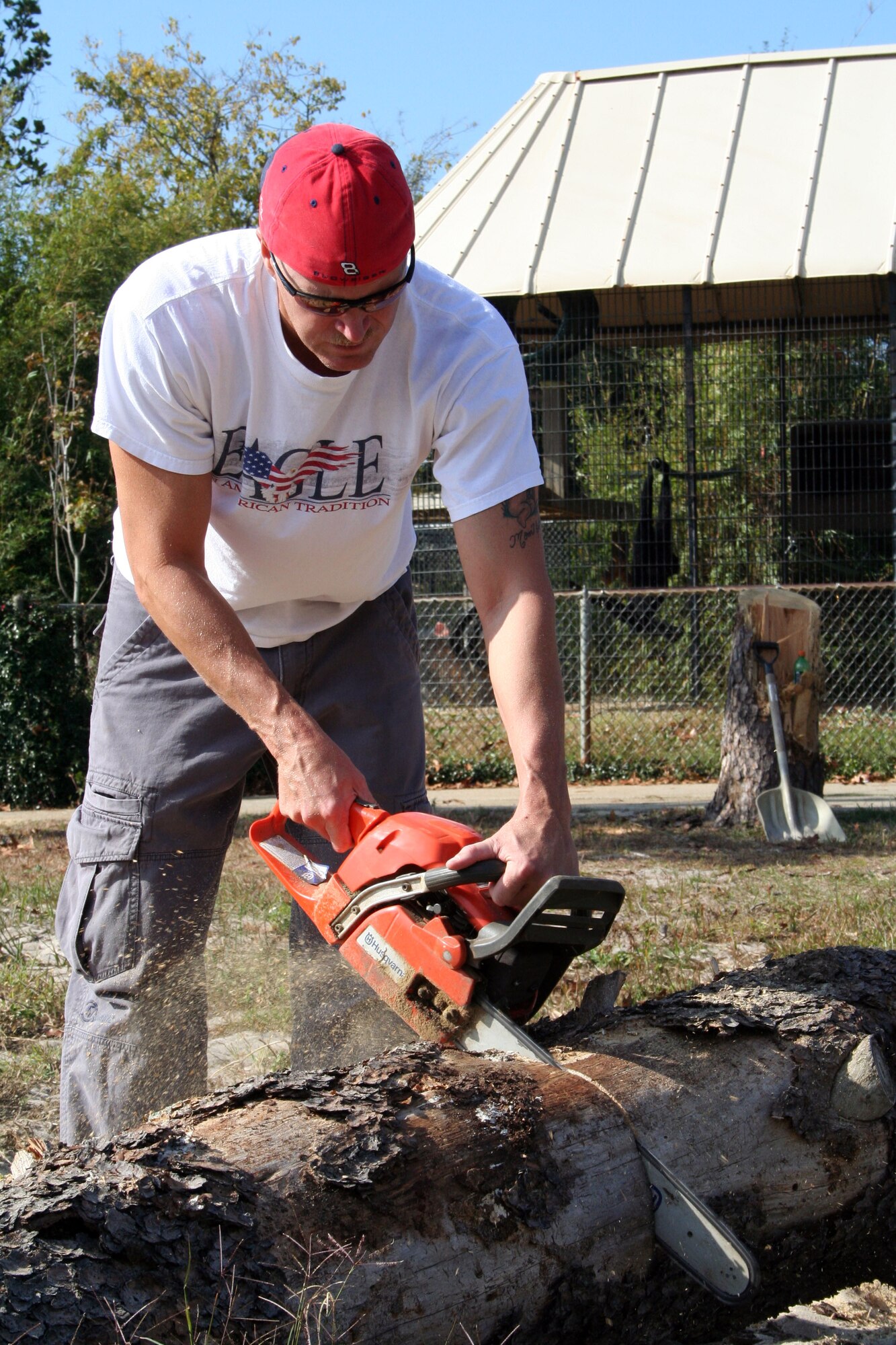 Master Sgt. Cristen Jackson, Air Force Special Operations Forces Air Operations Center, chops a log into more managable pieces at the Gulf Breeze Zoo Nov. 20 while a siamang monkey watches from the background. Ten volunteers from the AFSOF AOC transported wood to the zoo's preserve to be ground into mulch. (U.S. Air Force photo/2nd Lt. Lauren Johnson)